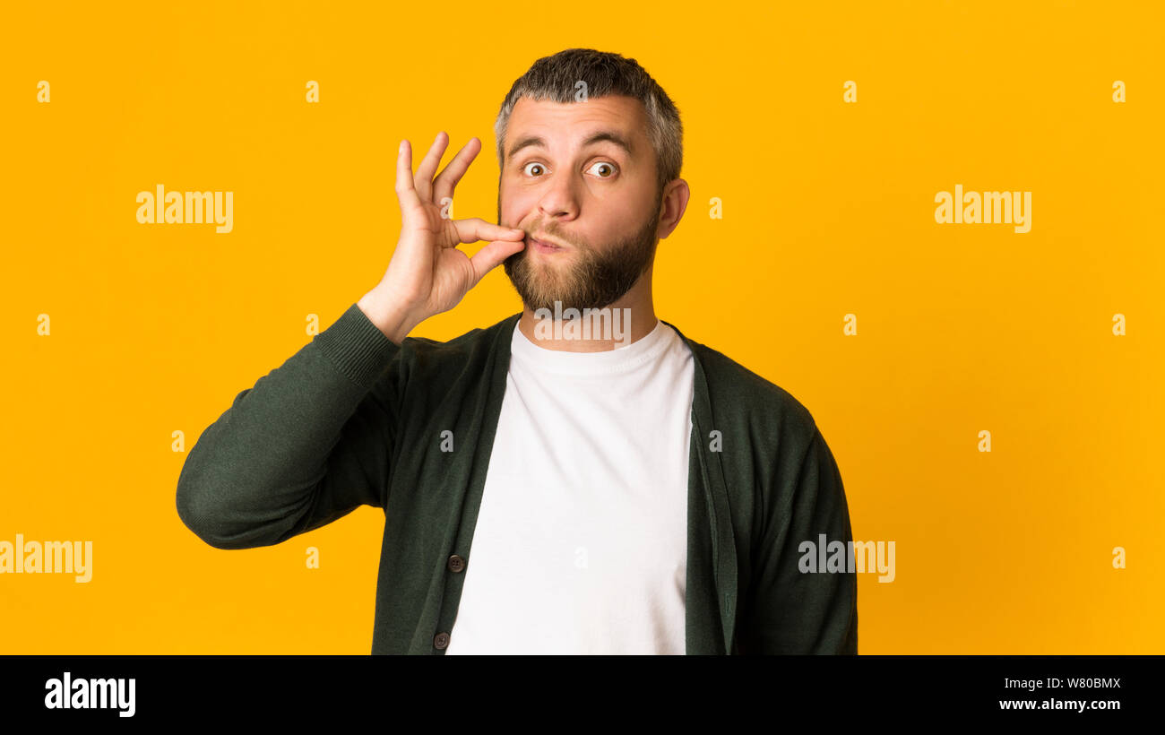 Stattlichen kaukasischen Mann seinen Mund zippen mit Geste Stockfoto