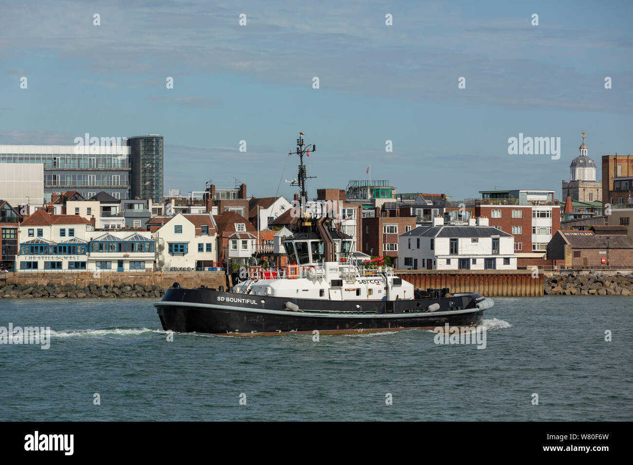 Serco tug SD energisch über den Hafen von Portsmouth. Leistungsstarke Schlepper verwendet, Schiffe der Royal Navy zu bewegen. Spice Island skyline hinter dem Boot. Stockfoto