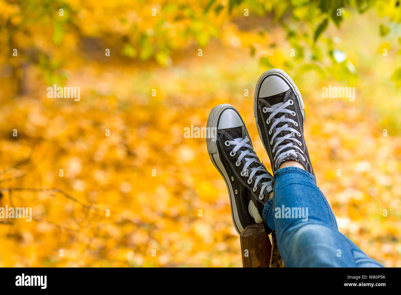 Entspannt Jugendmädchen Sneakers tragen liegt auf der Werkbank im Herbst park Nahaufnahme. Fokus auf Turnschuhe. Stockfoto