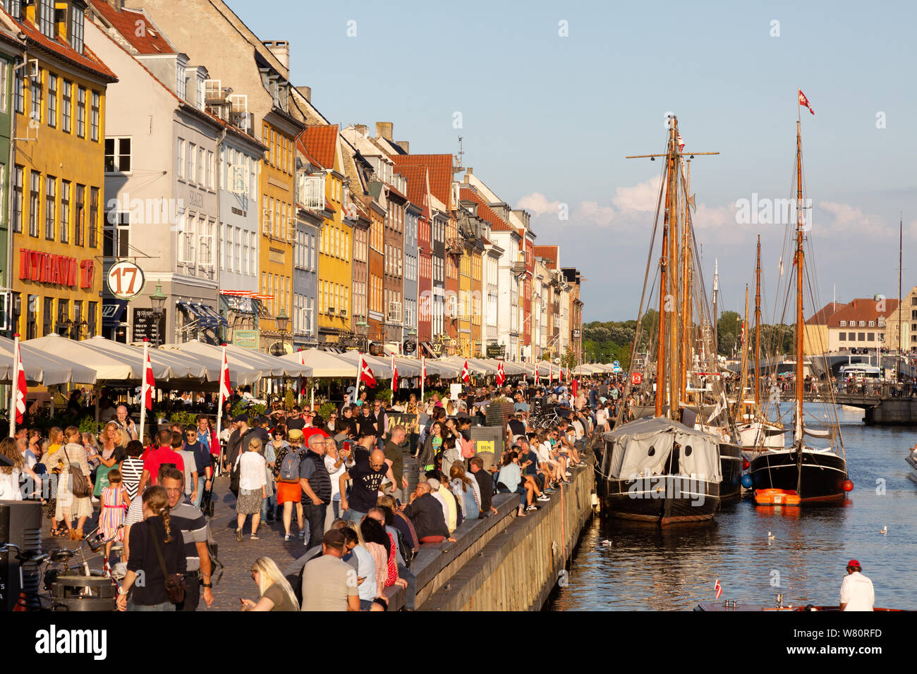 Europäische Reise; Boote, bunten Gebäuden und Massen von Menschen an einem sonnigen Sommerabend, Nyhavn Kopenhagen Dänemark Europa Stockfoto