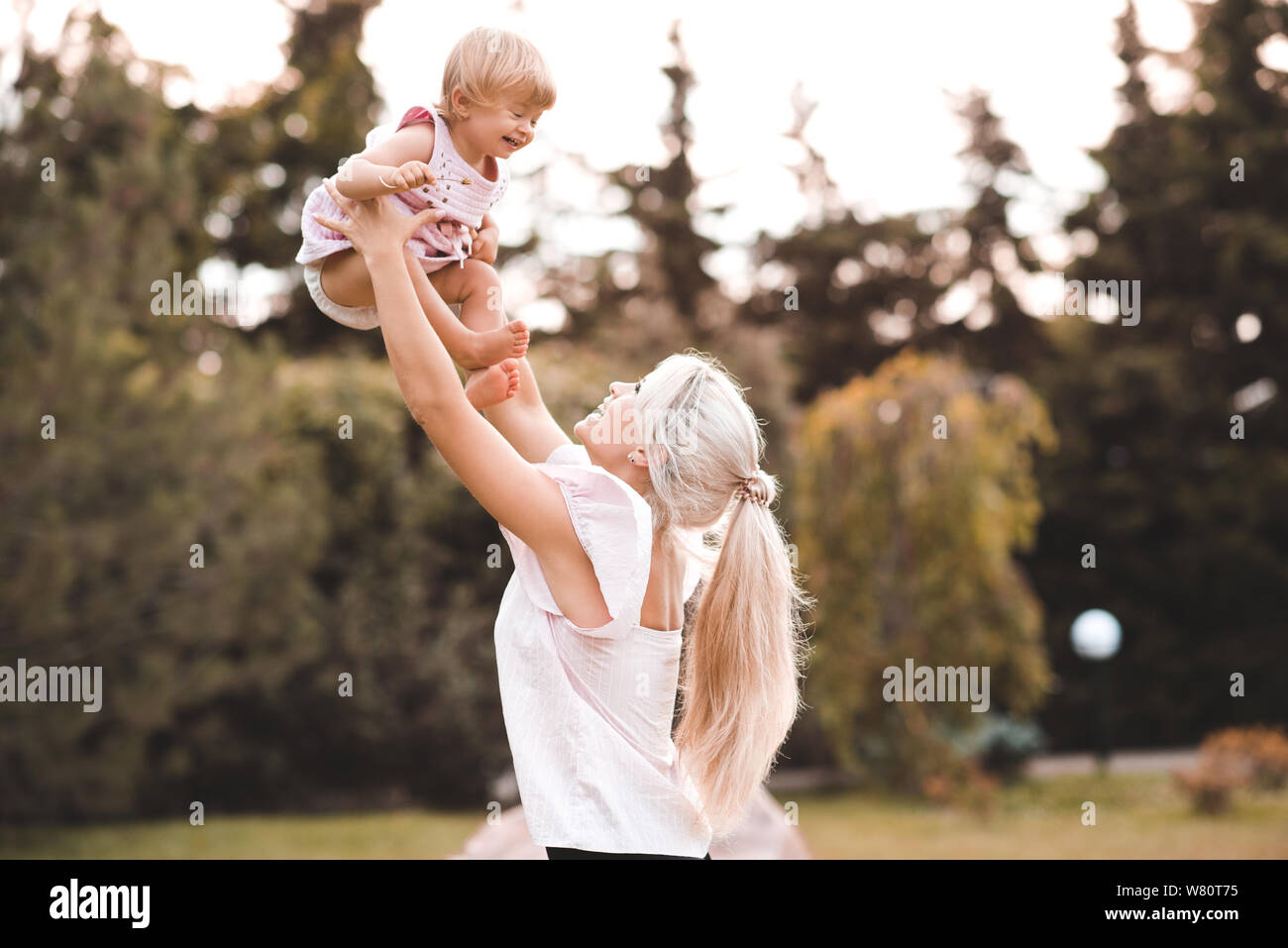 Glückliche Mutter spielt mit Baby Mädchen im Park im Freien. Die Mutterschaft. Mutterschaft. Stockfoto