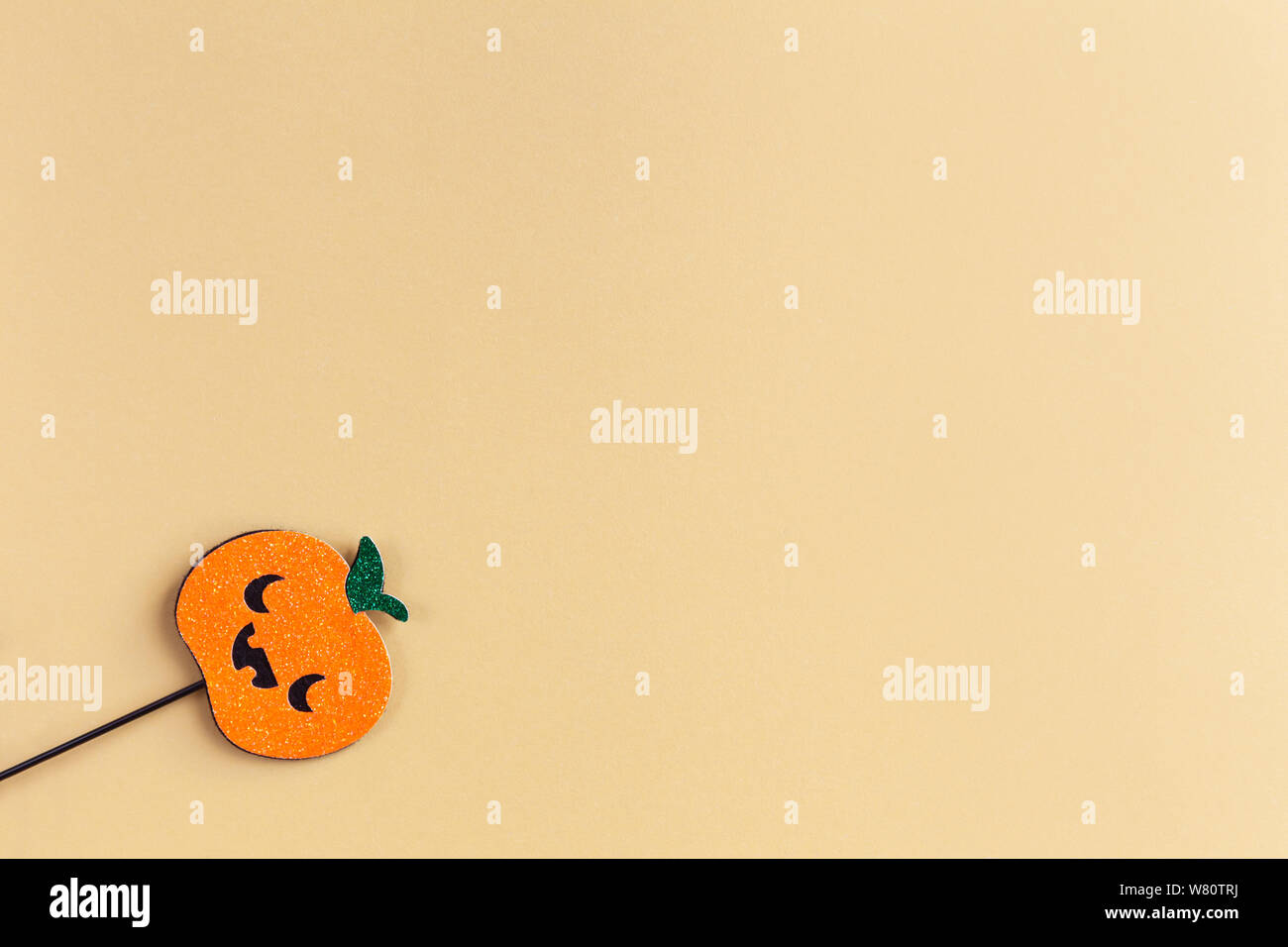 Halloween Party Zubehör, glänzende Kürbis mit niedlichen gruselige Gesichter. Pastell gelben Hintergrund, Platz für Text. Ferienwohnung legen. Minimalistischer Stil. Horizontale Stockfoto