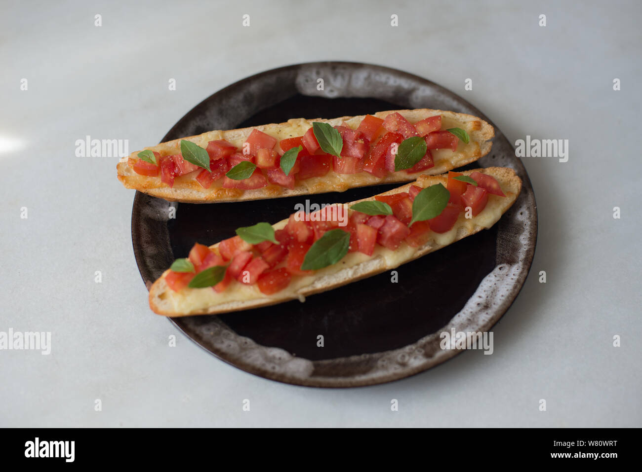 Bruschetta geschmolzenem Käse gehackten Tomaten Olivenöl schwarzer Pfeffer, natürliches Licht am Nachmittag. Foto in der Stadt Rio de Janeiro, Brasilien, 2019 übernommen. Stockfoto
