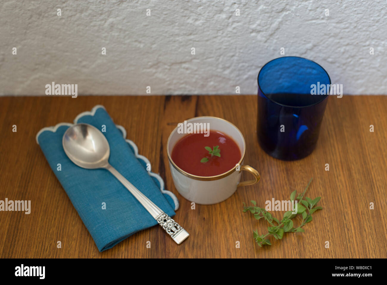 Italienische Tomatensuppe oregano Blätter Porzellan Silber Löffel Blau Leinen serviette Glas. Foto in der Stadt Rio de Janeiro, Brasilien, 2019 übernommen. Stockfoto