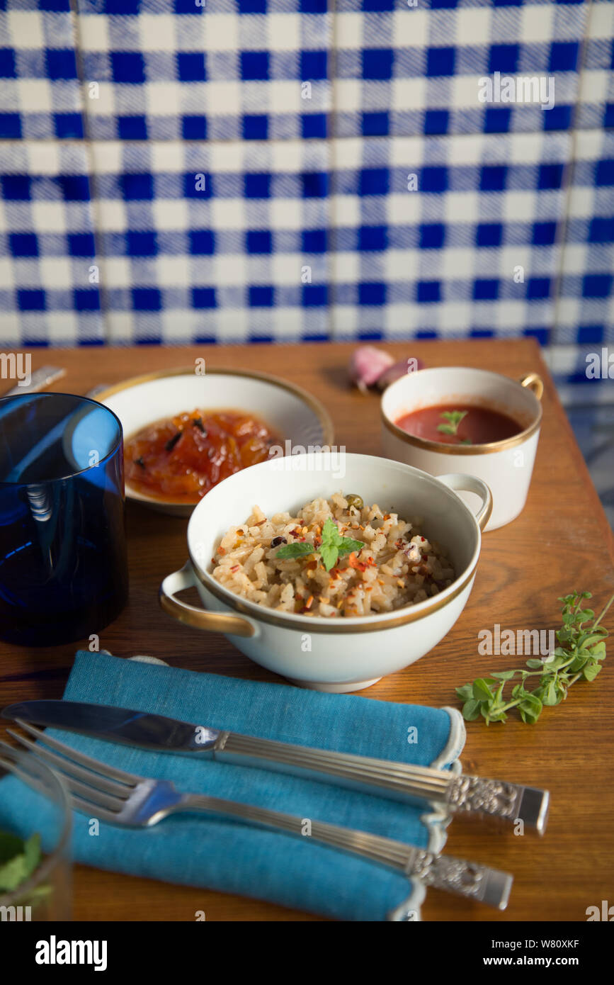 Italienische Tomatensuppe brauner Reis risotto Papaya dessert Porzellan Silber Besteck blau Leinen Serviette. Rio de Janeiro, Brasilien. Im Laufe des Jahres 2019. Stockfoto