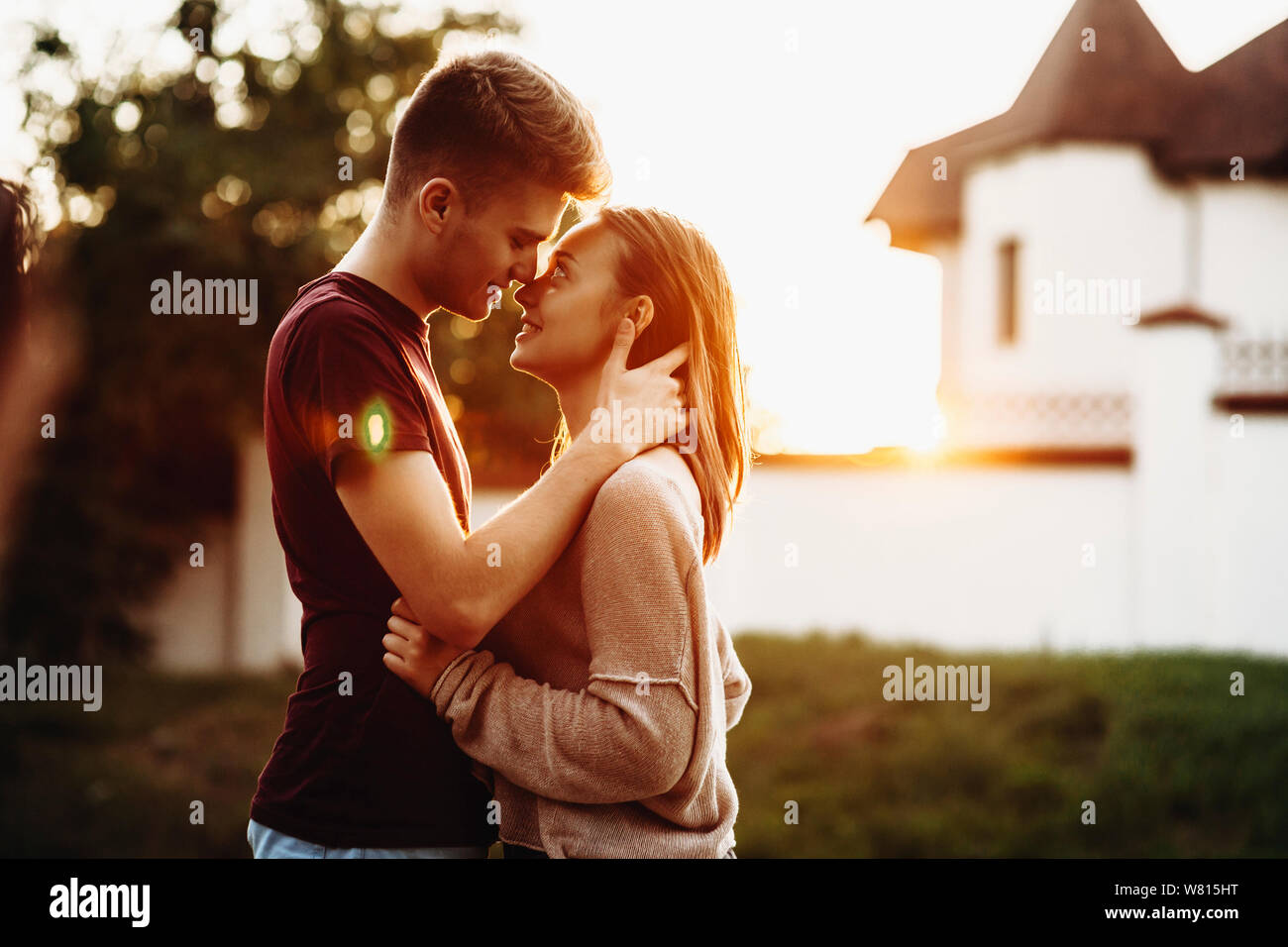 Seitenansicht eines niedlichen kaukasischen Paar umfassend gegen Sonnenuntergang und einem zum anderen suchen vor einem Schloss, während außerhalb zurückgehen. Stockfoto