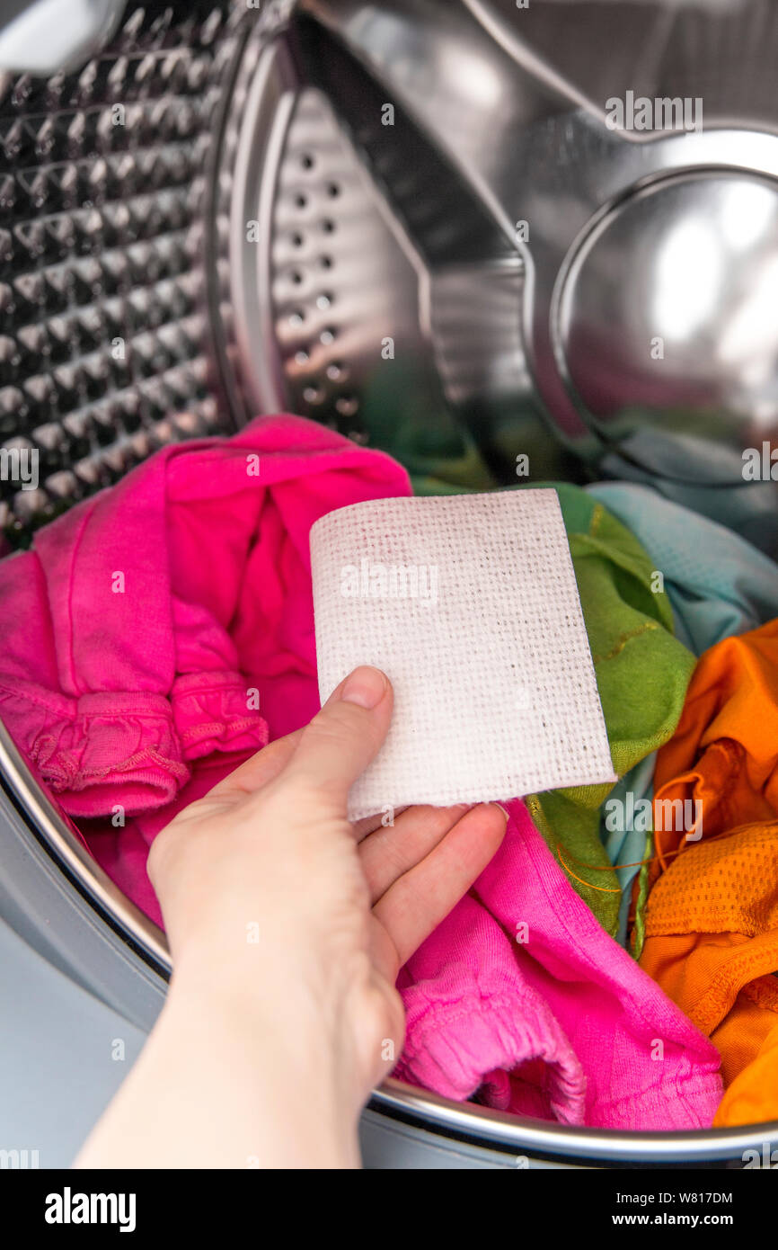 Frau hand Farbe saugfähiges Tuch in einer Waschmaschine geben, ermöglicht gemischten Farbe Kleidung ohne ruinieren Farben Konzept zu waschen. Stockfoto