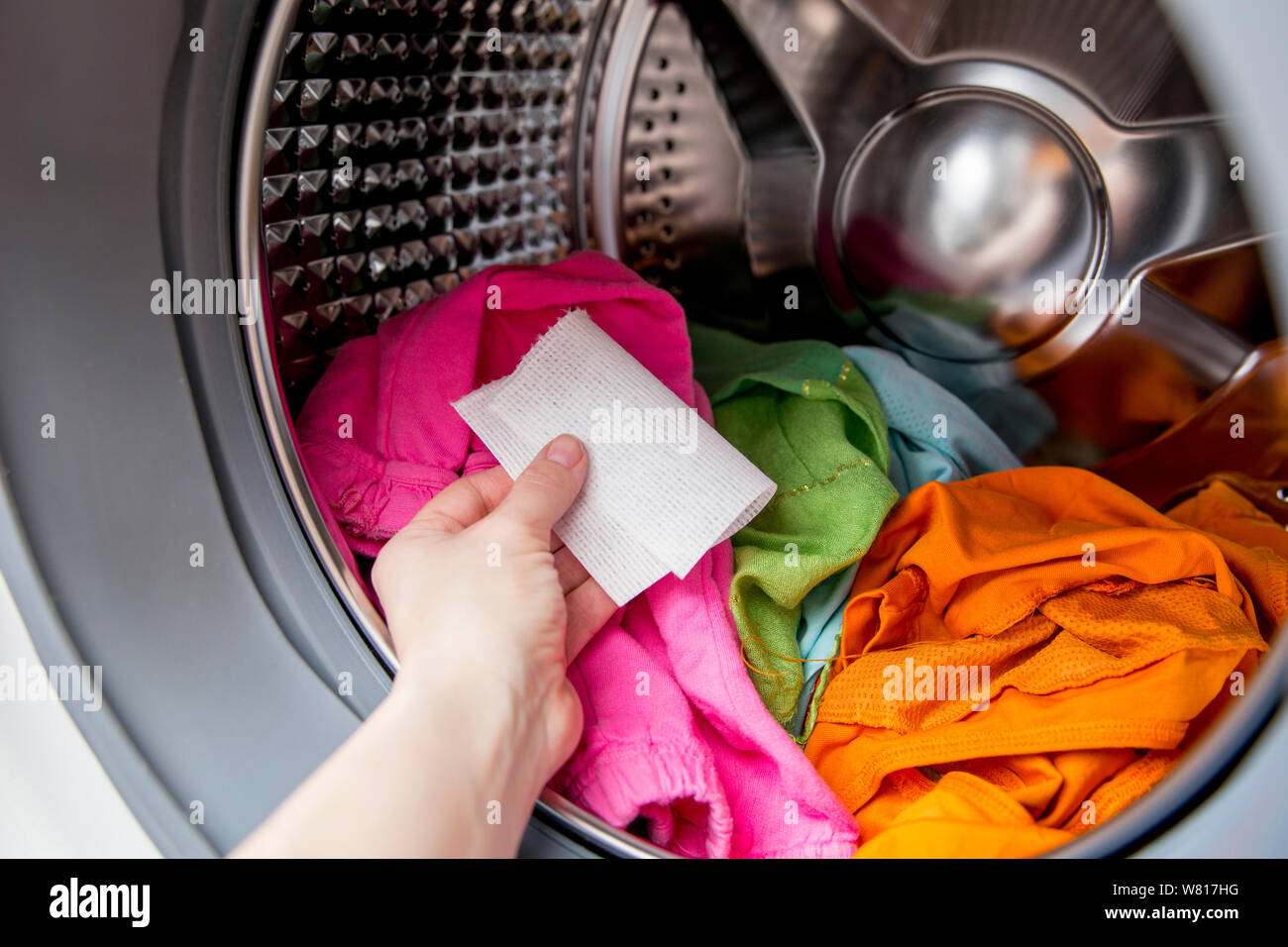 Frau hand Farbe saugfähiges Tuch in einer Waschmaschine geben, ermöglicht gemischten Farbe Kleidung ohne ruinieren Farben Konzept zu waschen. Stockfoto