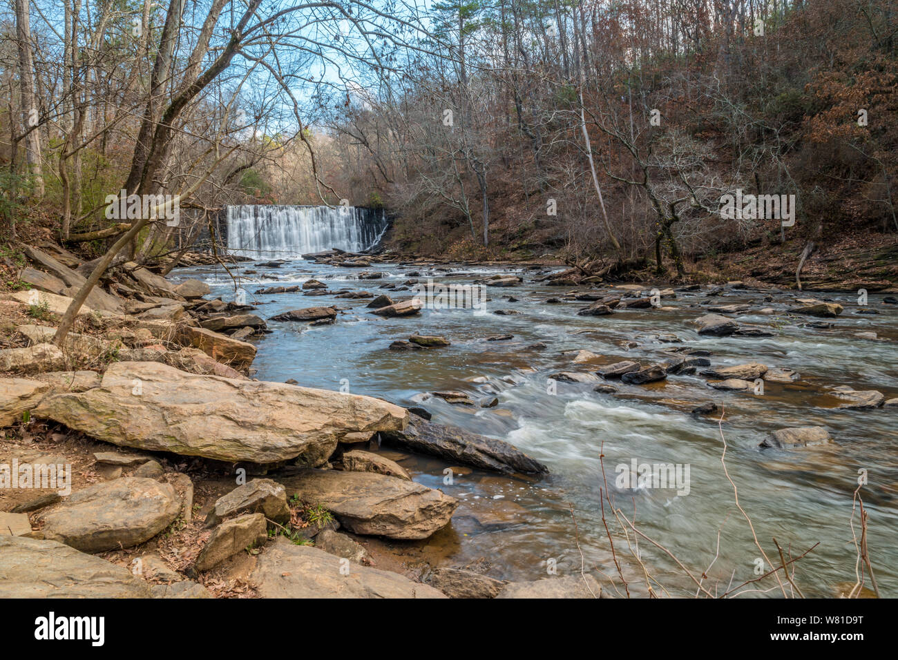 Offener Blick auf den Wasserfall im Winter an einem sonnigen Tag mit Felsen und Geröll im Vordergrund. Stockfoto