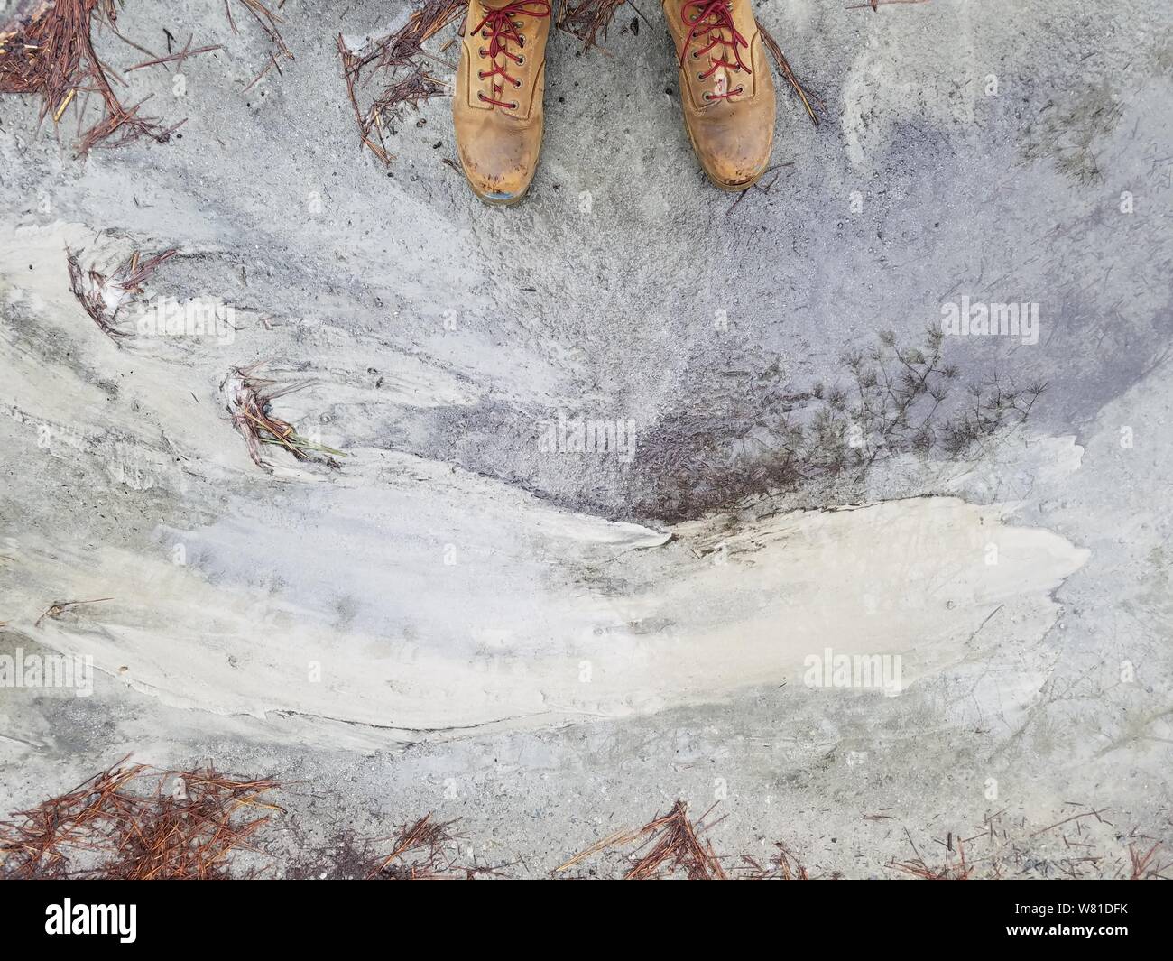 Die Füße der Person in braunen Lederschuhen, die auf einem verwitterten stehen Betonboden Stockfoto