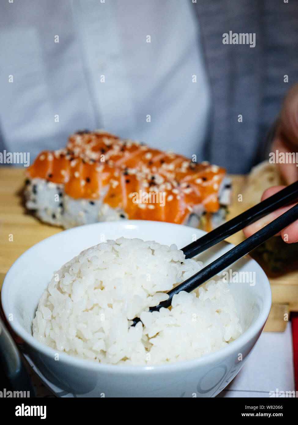 Vertikale Image der jungen Frau mit chinesischen Stäbchen Essen Maki Sushi japanische Küche Stockfoto
