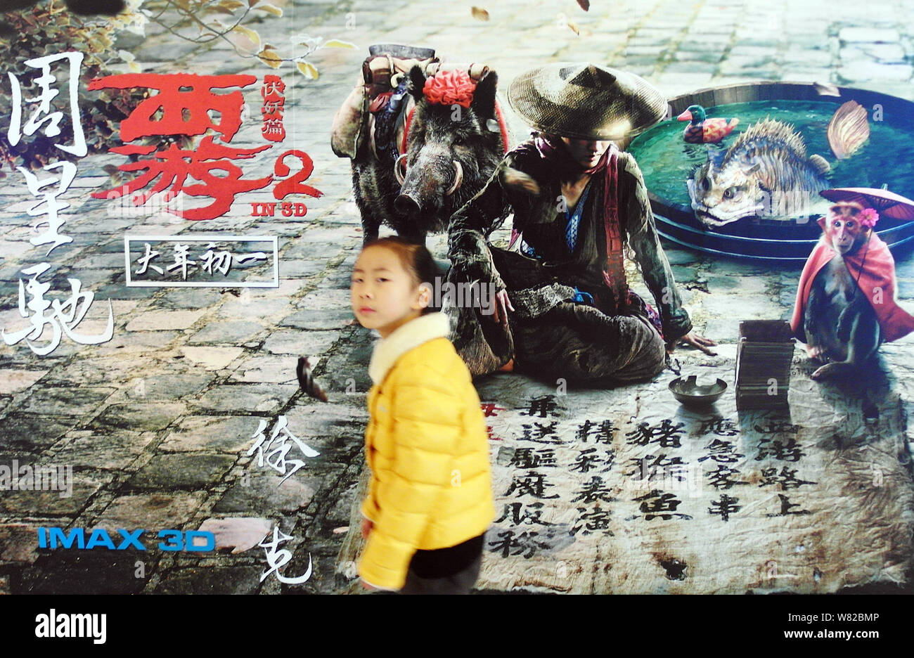 ---- Ein junges Mädchen geht hinter einem Plakat des Films "Die Reise nach Westen: Die Dämonen Schlagen zurück" in einem Kino in Kunshan City, Central China Hubei Stockfoto