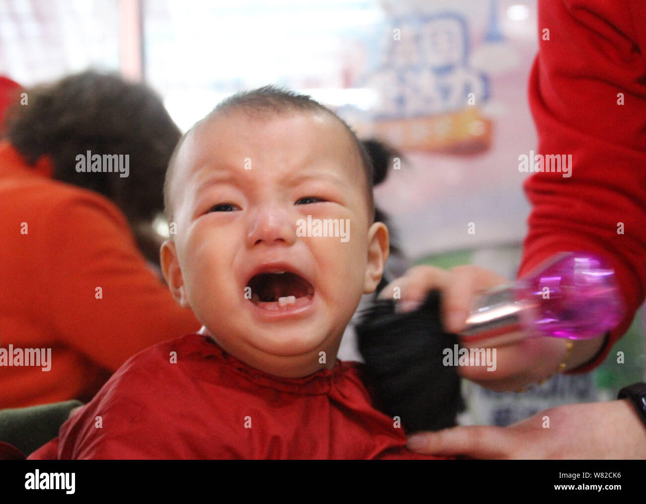 Ein junger chinesischer Junge weint, während sich die Haare schneiden die Longtaitou Festival, auch bekannt als die Drachen - und Tag, im Boxen in der Grafschaft zu feiern. Stockfoto