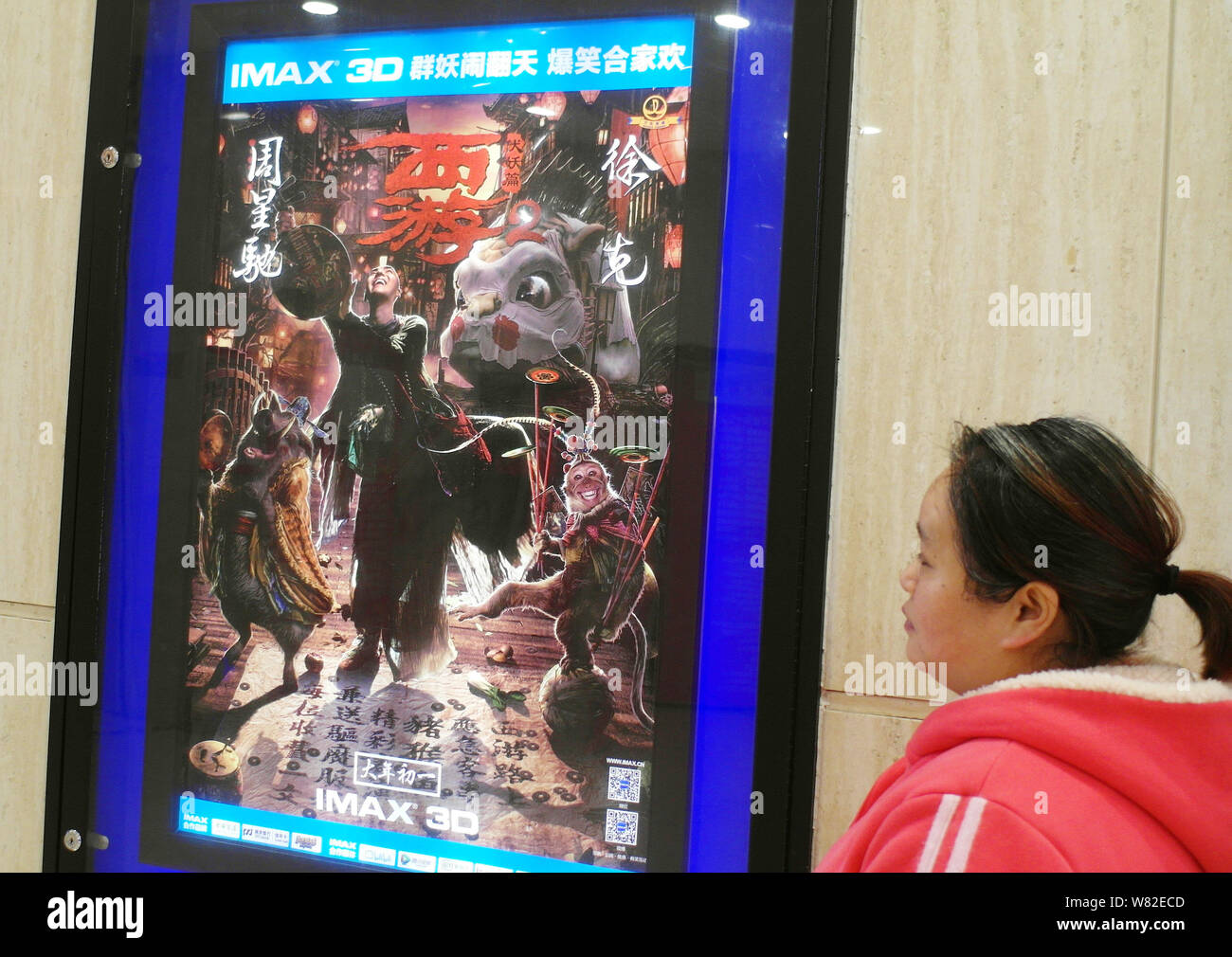 ---- Eine Chinesische filmgoer Spaziergänge hinter einem Plakat des Films "Die Reise nach Westen: Die Dämonen Schlagen zurück" in einem Kino in Kunshan City, Central Chinas Stockfoto