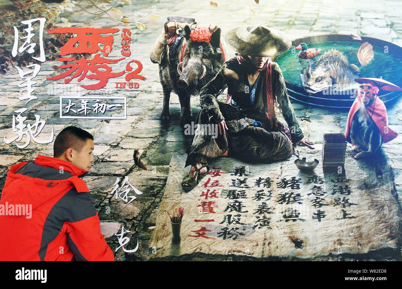 ---- Ein kleiner Junge geht hinter einem Plakat des Films "Die Reise nach Westen: Die Dämonen Schlagen zurück" in einem Kino in Kunshan City, Central China Hubei Stockfoto