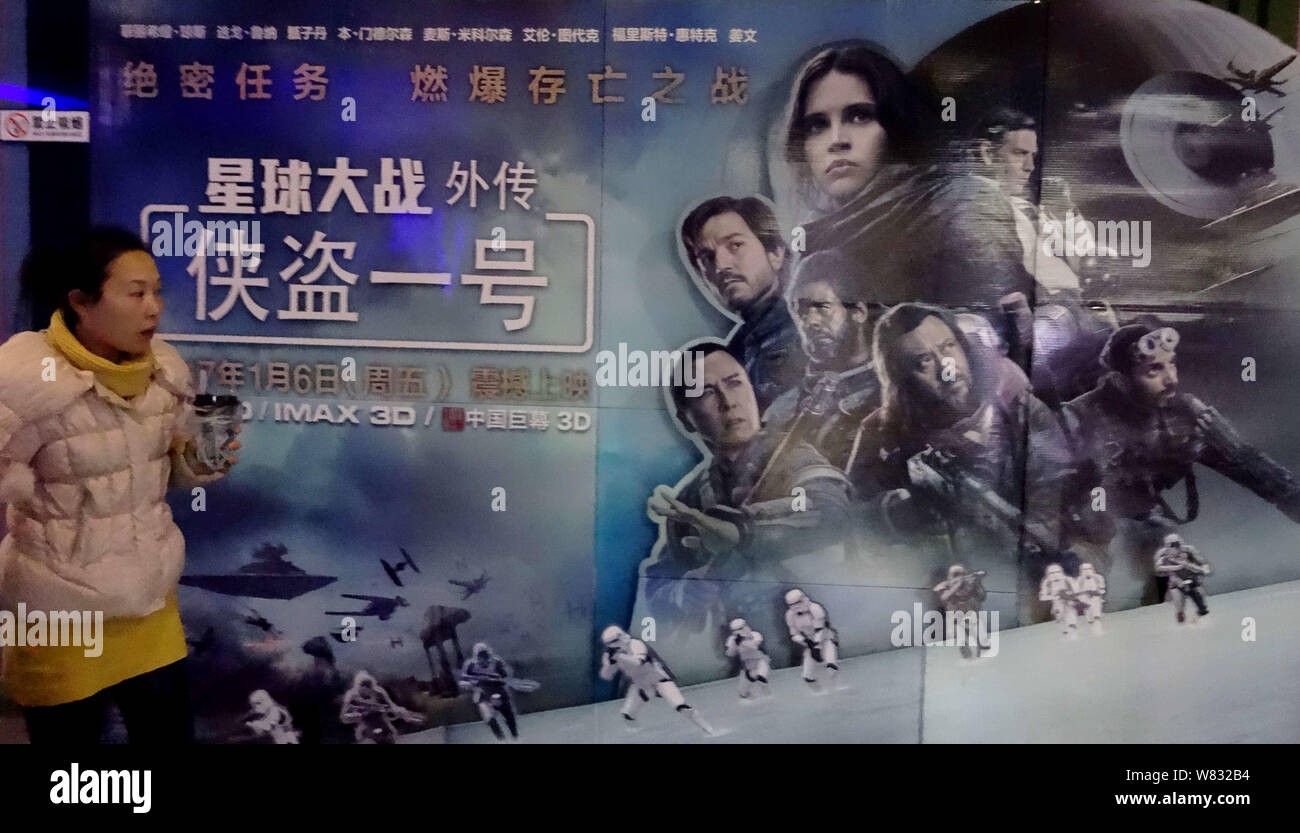 Eine Chinesische filmgoer Spaziergänge hinter einem Plakat des Films "Schurkenstaaten: ein Star Wars Geschichte" in einem Kino in Kunshan City, Central China Provinz Hubei, 1 Janu Stockfoto