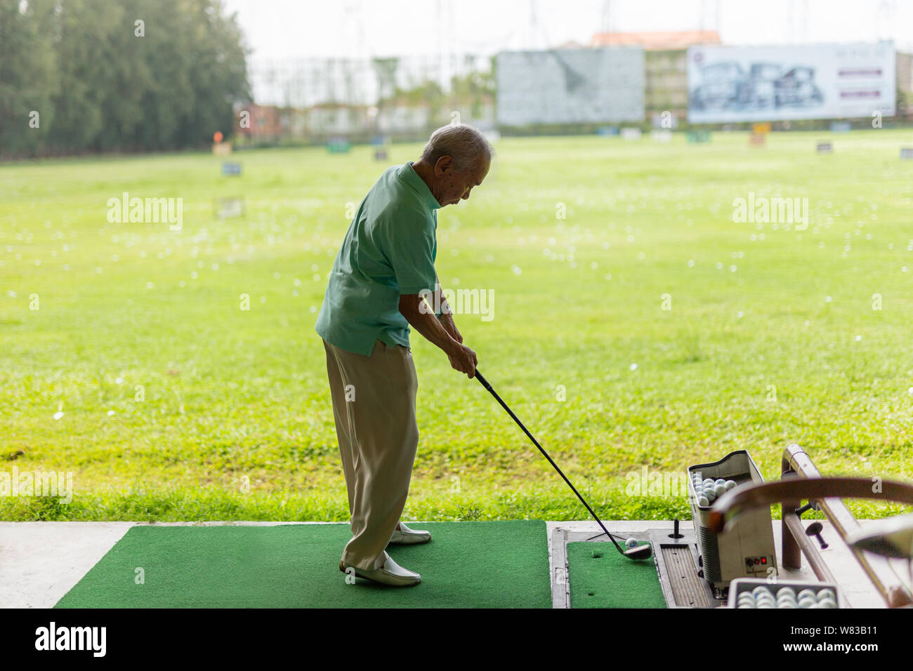 Bangkok Thailand - älterer Mann Übung üben sein Golf an der Golf Driving Range. Stockfoto