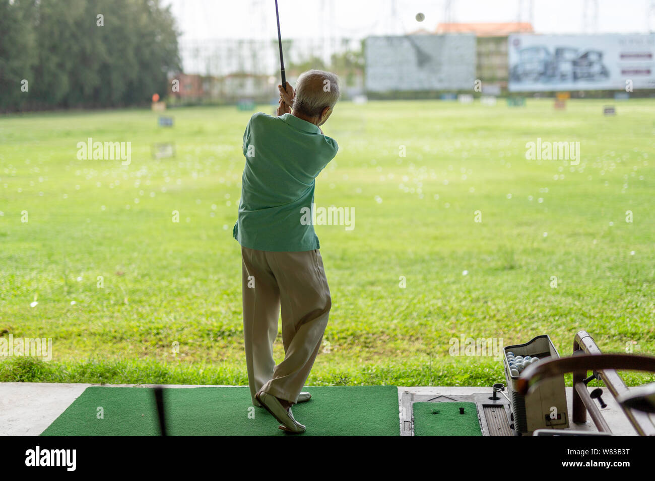 Älterer mann Übung üben sein Golf schwingen am golf driving range. Stockfoto