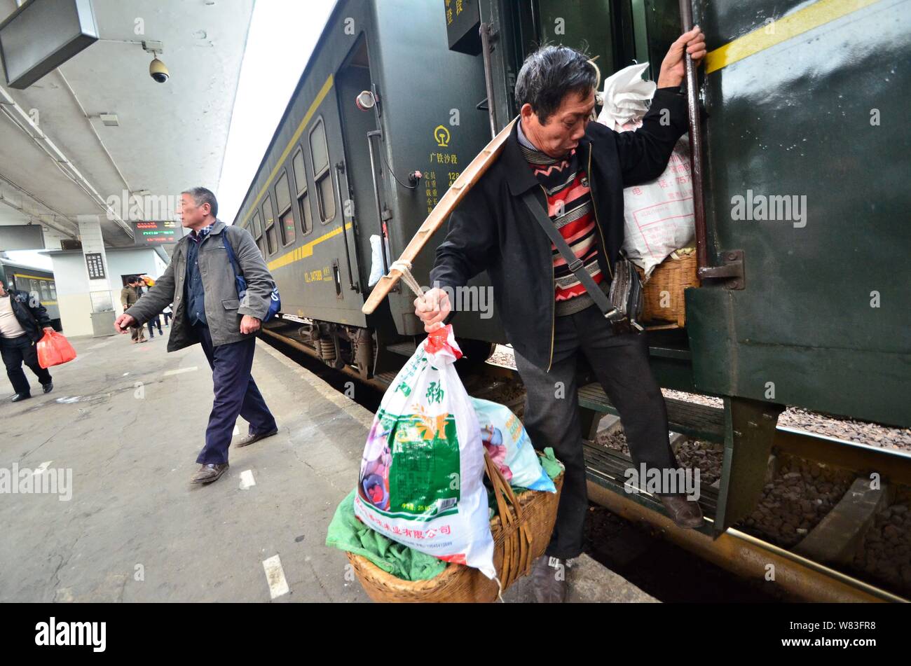 Ein chinesischer Bauer die Körbe mit Gemüse wird aus einem "pflanzlich Landwirt Train' auf der Beijing-Guangzhou (oder Jingguang) Bahnstrecke am Chenzh Stockfoto