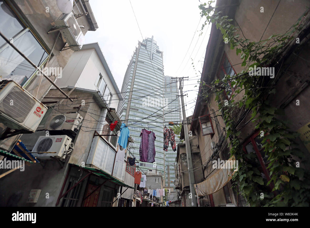 ------ Kleidung aufhängen an den Kabeln für die Trocknung über einen Weg zu einem Elendsviertel mit alten Häusern für den Wiederaufbau in Shanghai, China, 27 Ju demontiert werden Stockfoto