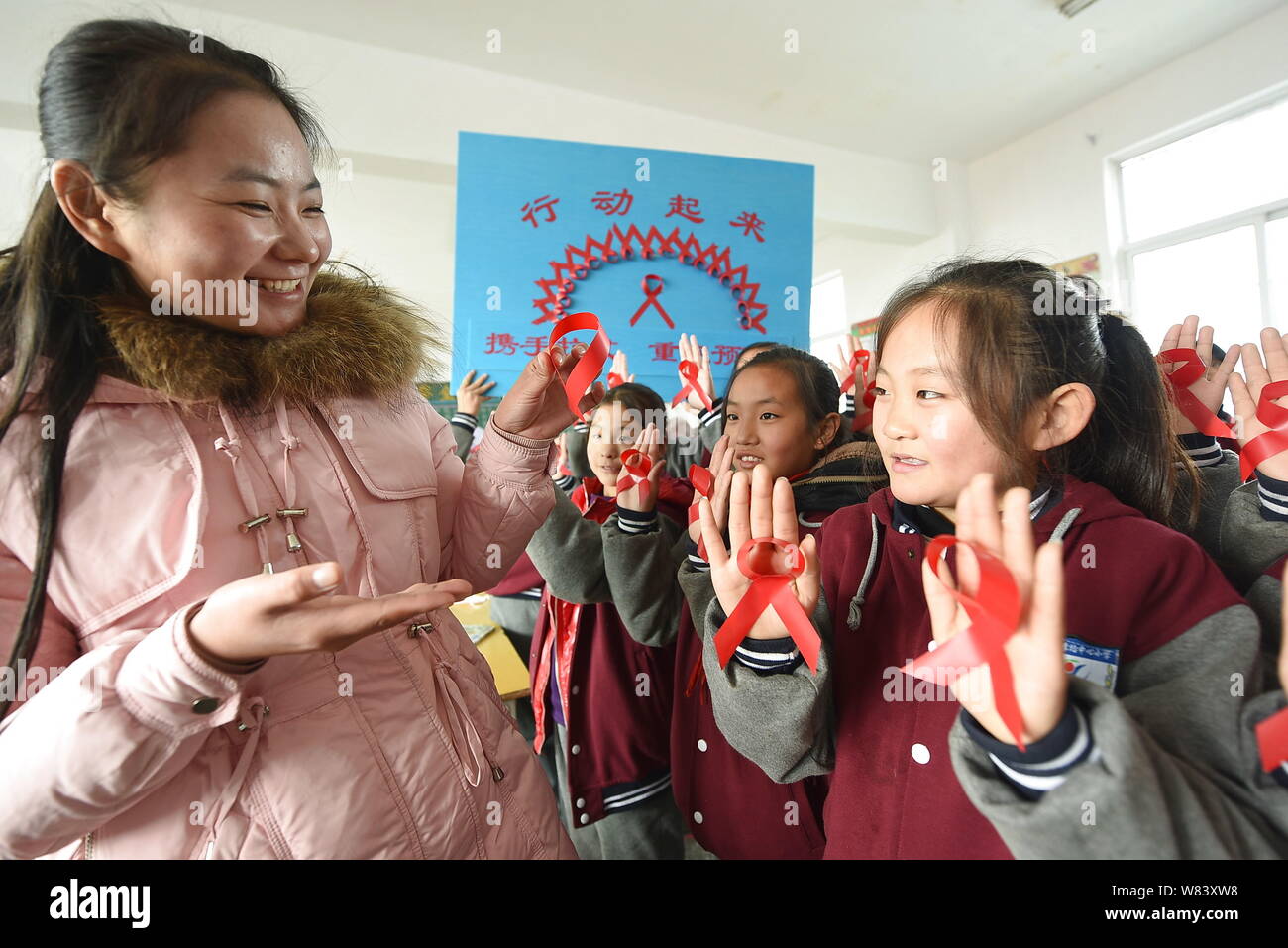Eine chinesische Lehrerin zeigt ein rotes Band und propagandizes Vorbeugung von HIV und AIDS für junge Schüler im Klassenzimmer an einer Grundschule im Li Stockfoto