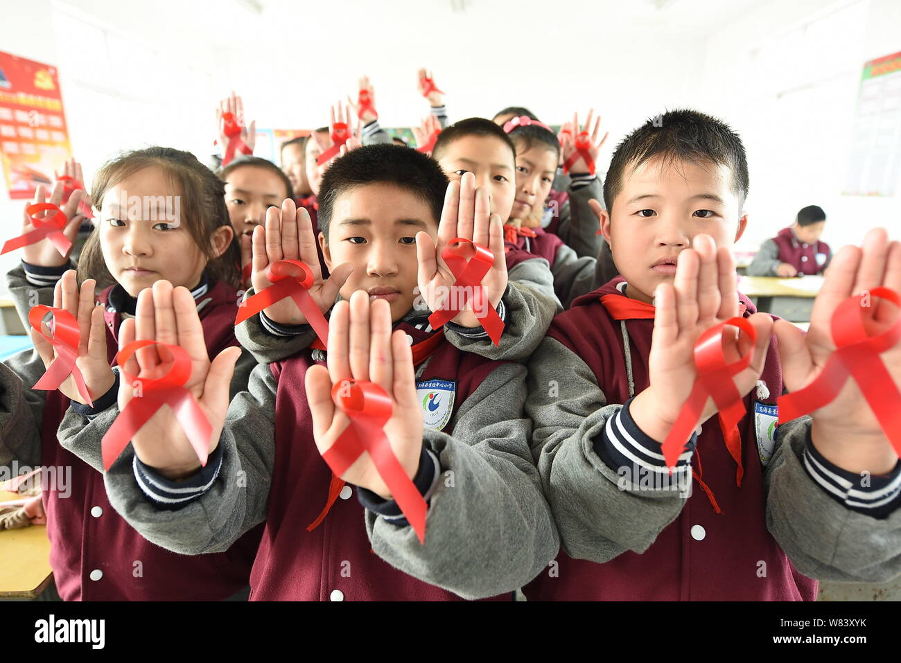 Junge chinesische Studenten zeigen rote Bänder, wie sie Vorbeugung von HIV und AIDS lernen Welt-AIDS-Tag im Klassenzimmer an einer Grundschule in Linia zu markieren Stockfoto