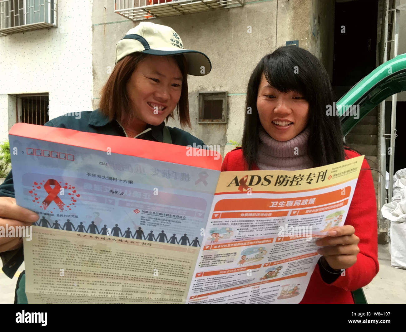 Eine Chinesische postwoman stellt eine Broschüre Propaganda Vorbeugung von HIV und AIDS von einem Ortsansässigen in Liuxu Stadt, Hechi City, South China Guangx Stockfoto