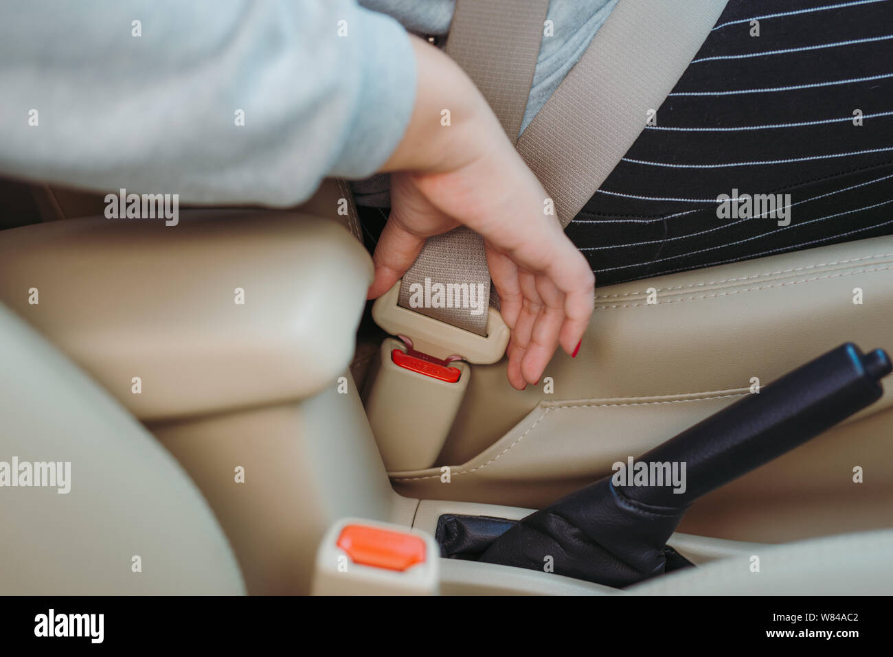 Zugeschnittenes Bild einer Frau im Auto sitzen und auf ihren Sicherheitsgurt Stockfoto