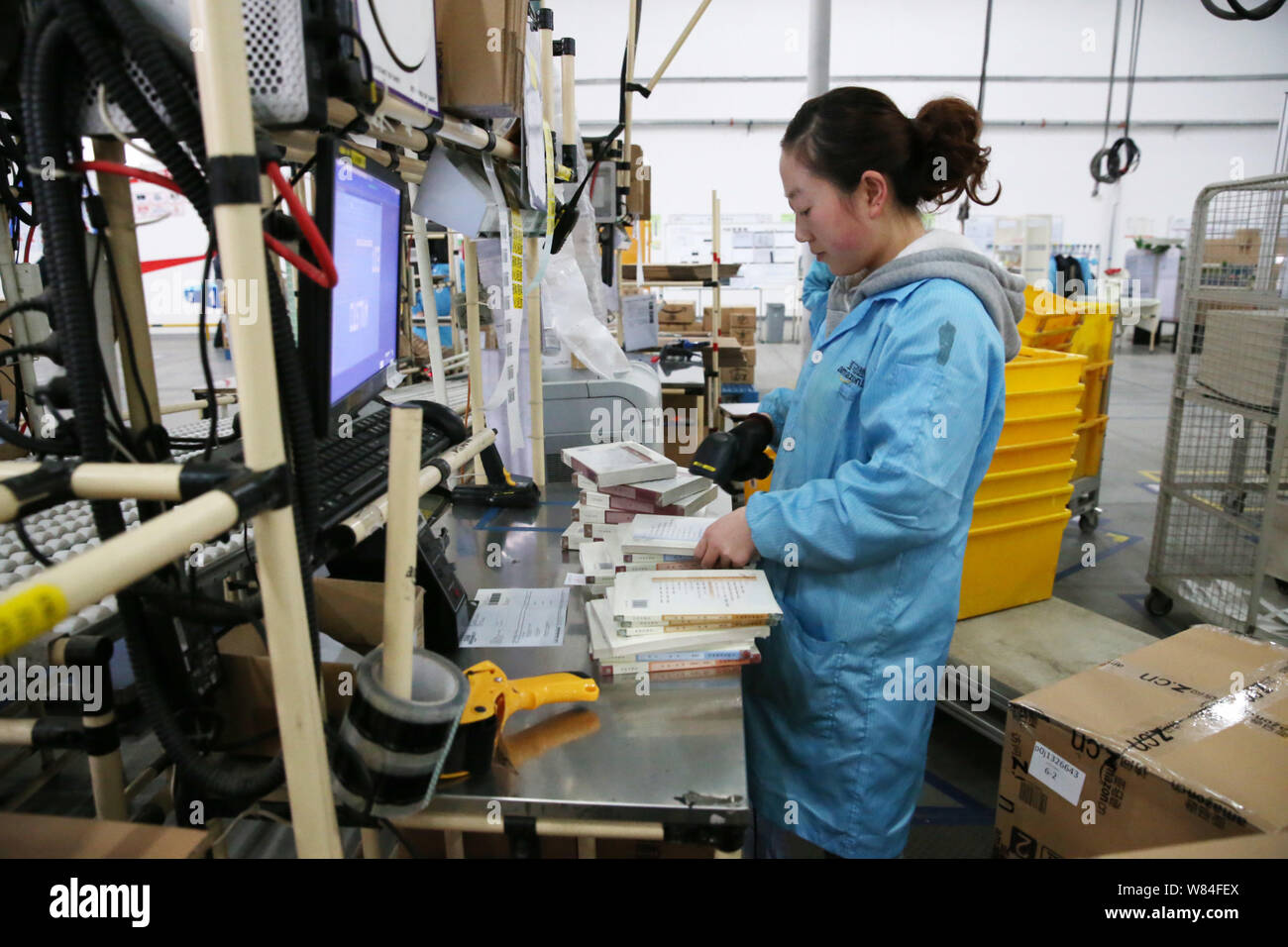 ---- Ein chinesischer Mitarbeiter bereitet sich Bücher für Online Bestellungen bei einer Erfüllung von Amazon in Deyang Stadt, im Südwesten Chinas Provinz Sichuan, 10. Stockfoto