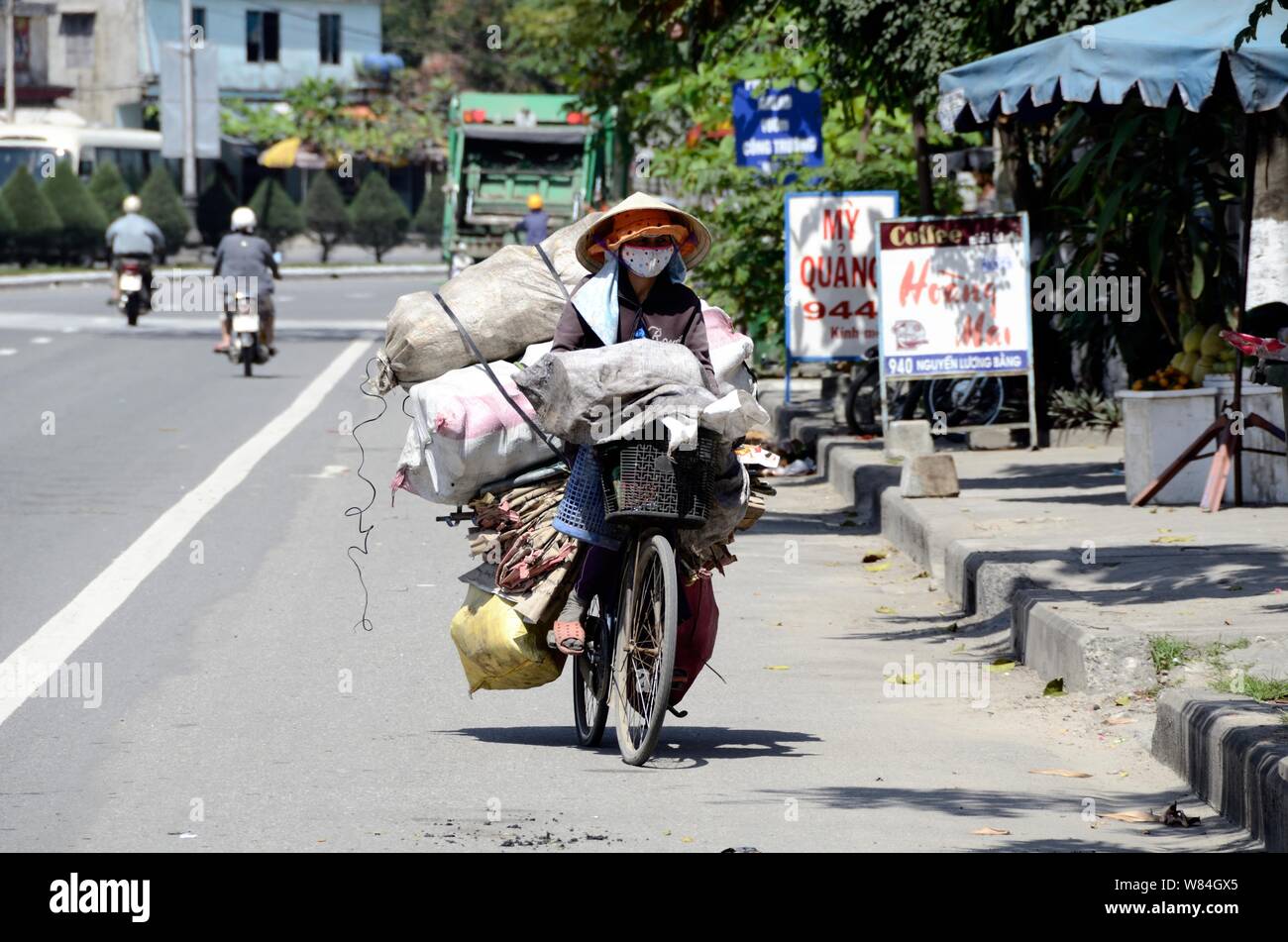 Vietnamesische Bauern Spaziergänge auf Ihre stark Fahrrad auf der Mandarine Straße geladen Stockfoto