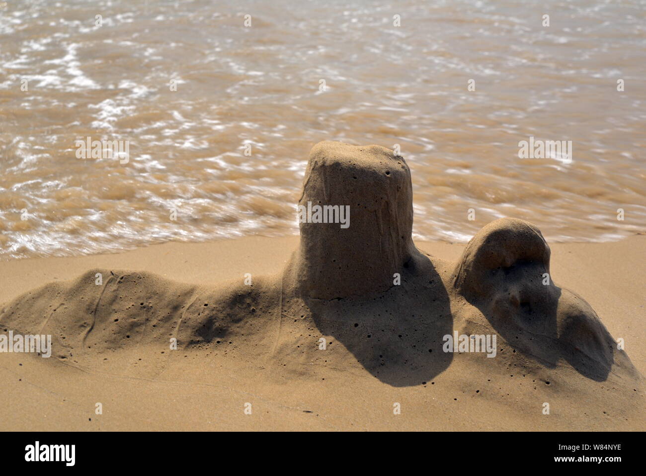 Sandburgen, die von den Meereswellen gestürzt wurden Stockfoto