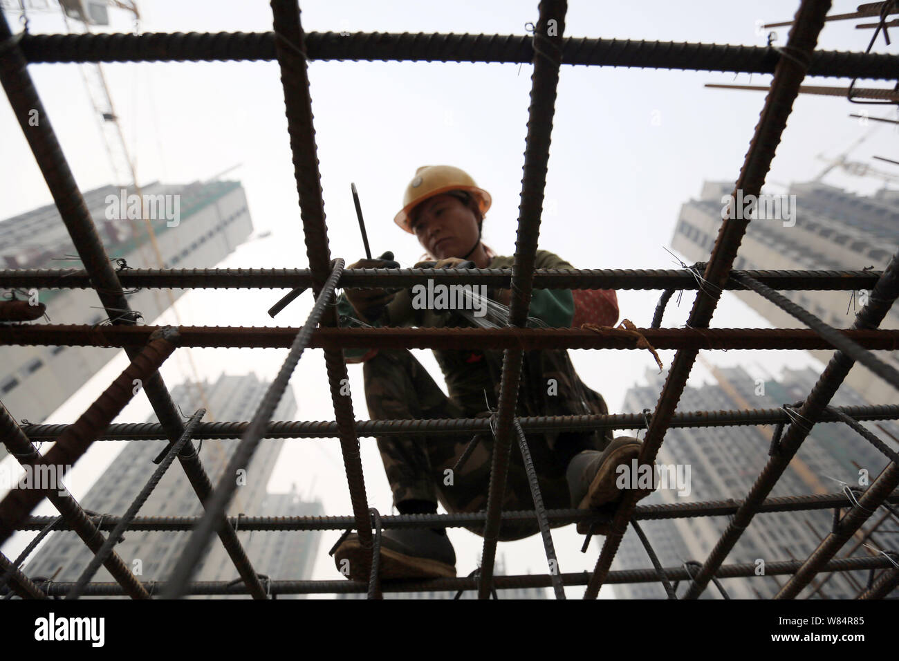 ---- Eine weibliche Chinesische Wanderarbeiter bindet das Verstärken von Stahl Stäbe auf der Baustelle eine Wohn- Projekt in Stadt Xingtai, Nord Stockfoto