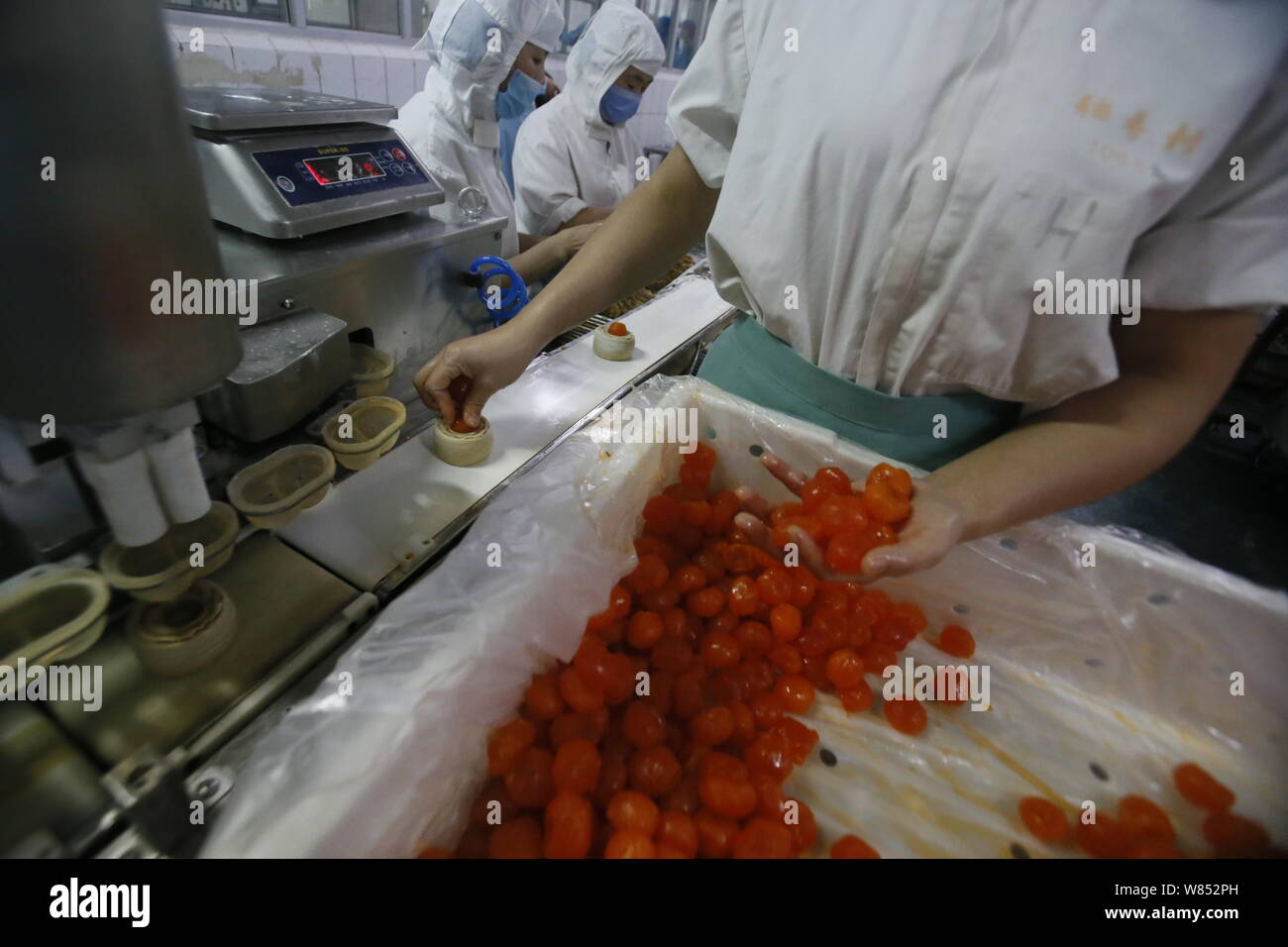 Ein chinesischer Arbeiter fügt Füllung in Teig mooncakes für die kommenden Mid-Autumn Festival in einem Lebensmittel verarbeitenden Betrieb von Peking Daoxiangcun Foo zu machen Stockfoto