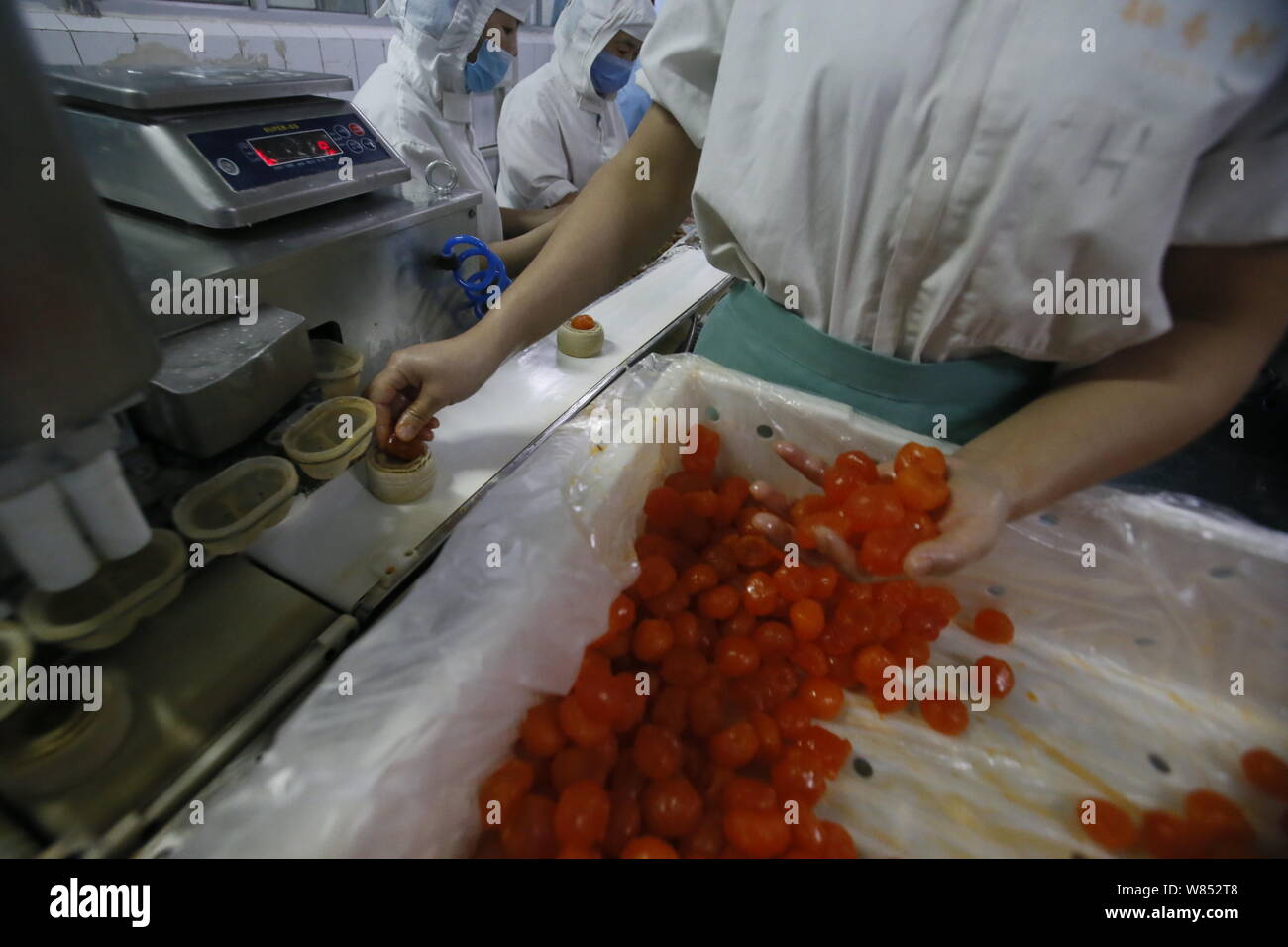 Ein chinesischer Arbeiter fügt Füllung in Teig mooncakes für die kommenden Mid-Autumn Festival in einem Lebensmittel verarbeitenden Betrieb von Peking Daoxiangcun Foo zu machen Stockfoto