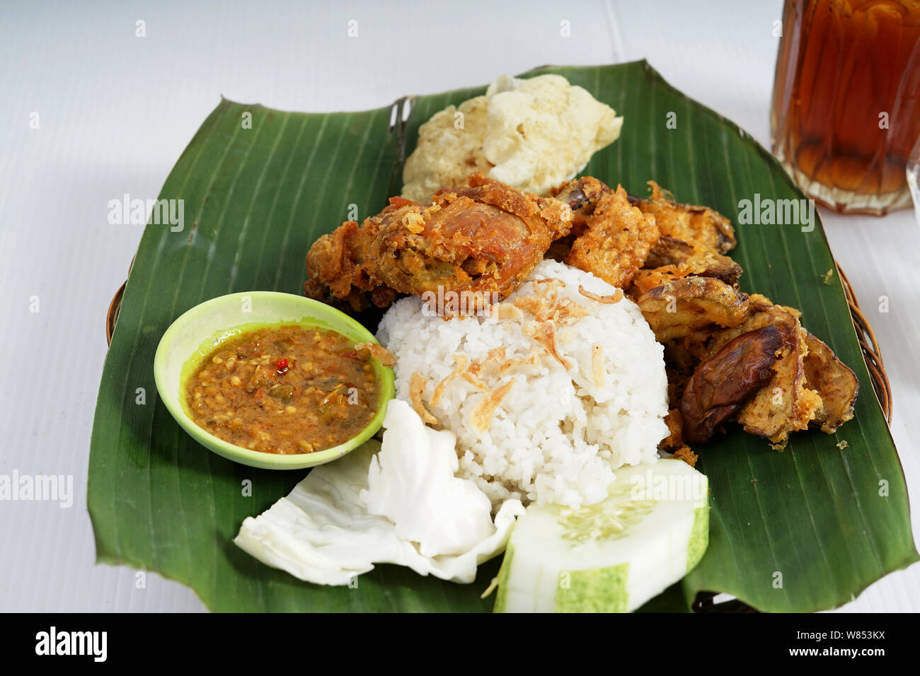 Leckere asiatische Ayam Penyet oder zertrümmerte gebratenes Huhn mit Eis Tee aus Indonesien Stockfoto