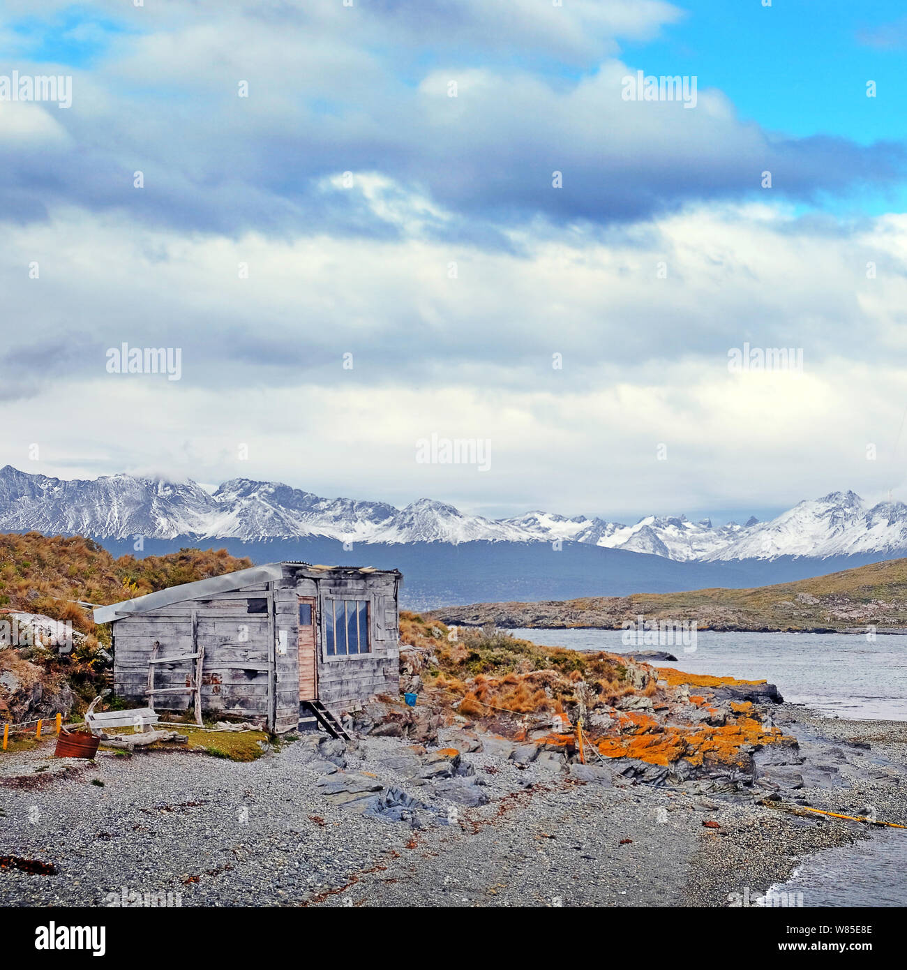 Anzeigen eines verlassenen Hauses und die patagonische Bergwelt von einer Insel von braun und orange Vegetation auf den Beagle Kanal, in der Nähe der Stadt Stockfoto