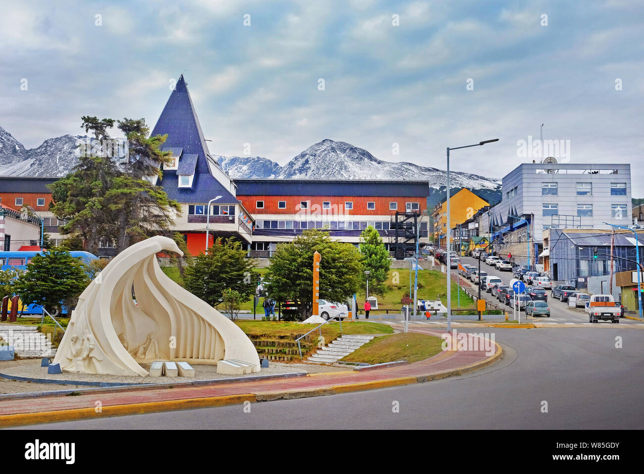 Urbane Landschaft von einem Denkmal und Menschen zu Fuß auf den Straßen in der Nähe der bunten Gebäude in der Innenstadt von Ushuaia, Feuerland, Argentinien, Stockfoto