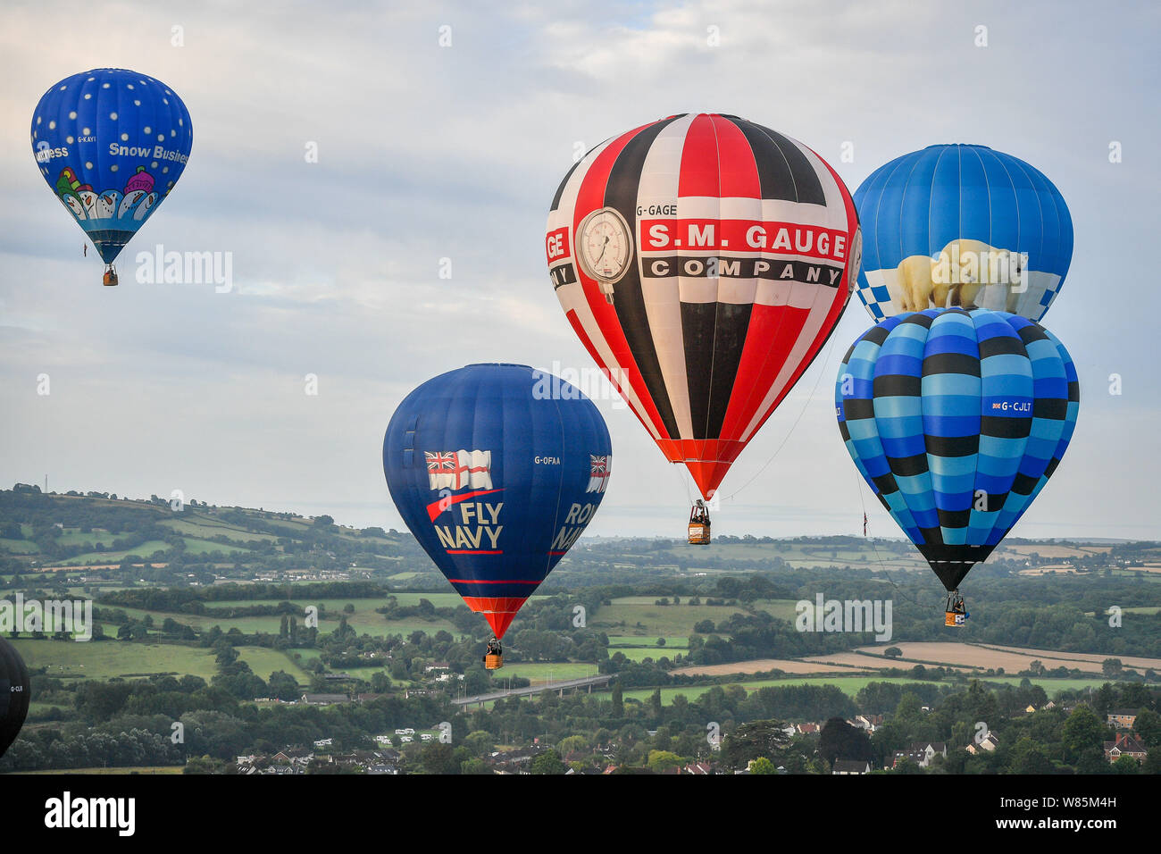 Luftballons schweben über Ashton Hof Immobilien in der ersten Donnerstag Masse Aufstieg an der Bristol International Balloon Fiesta, wo hunderte von Ballons hoffen, über das Wochenende vor der vorhergesagten Stürme über England zu fliegen. Stockfoto