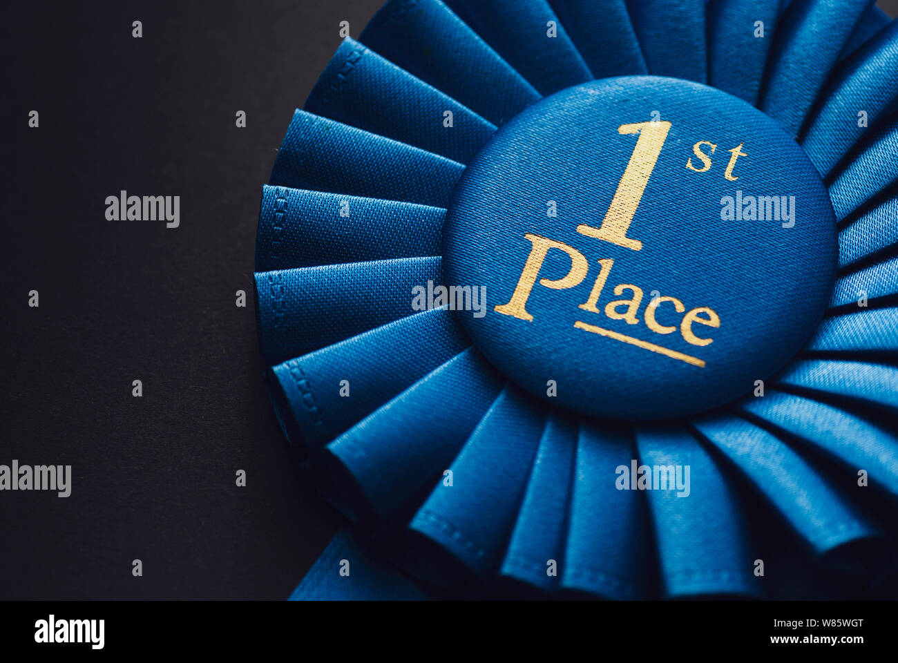 Meister Platz 1 blaue Rosette mit gold Text auf schwarzem Hintergrund Stockfoto