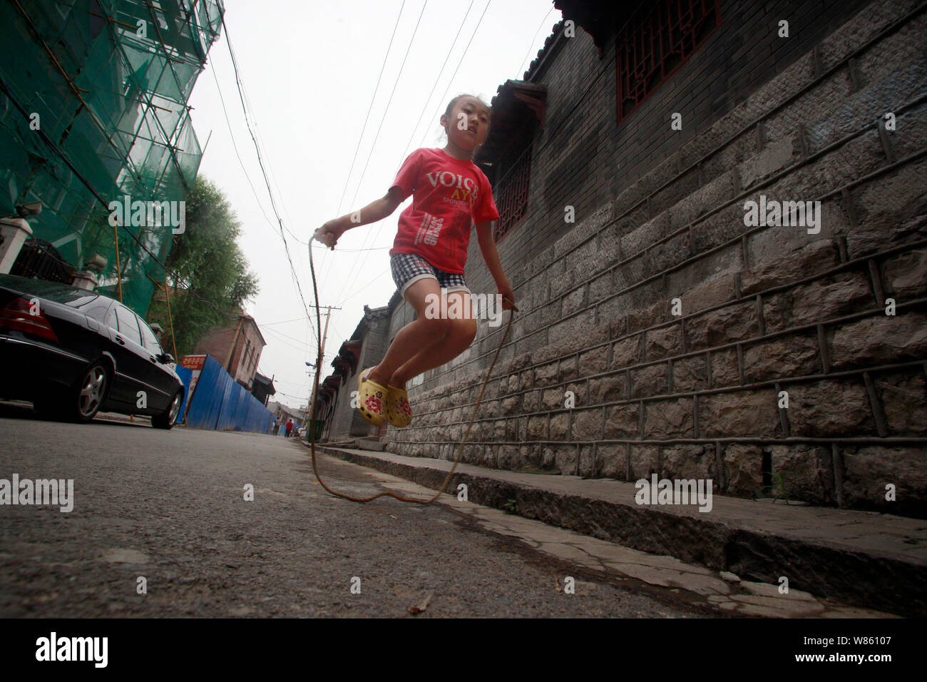 Sieben Jahre alten Mädchen Liang Yuxin spielt Seilspringen in einem Hutong in Ji'Nan, der ostchinesischen Provinz Shandong, den 2. August 2016. Stockfoto