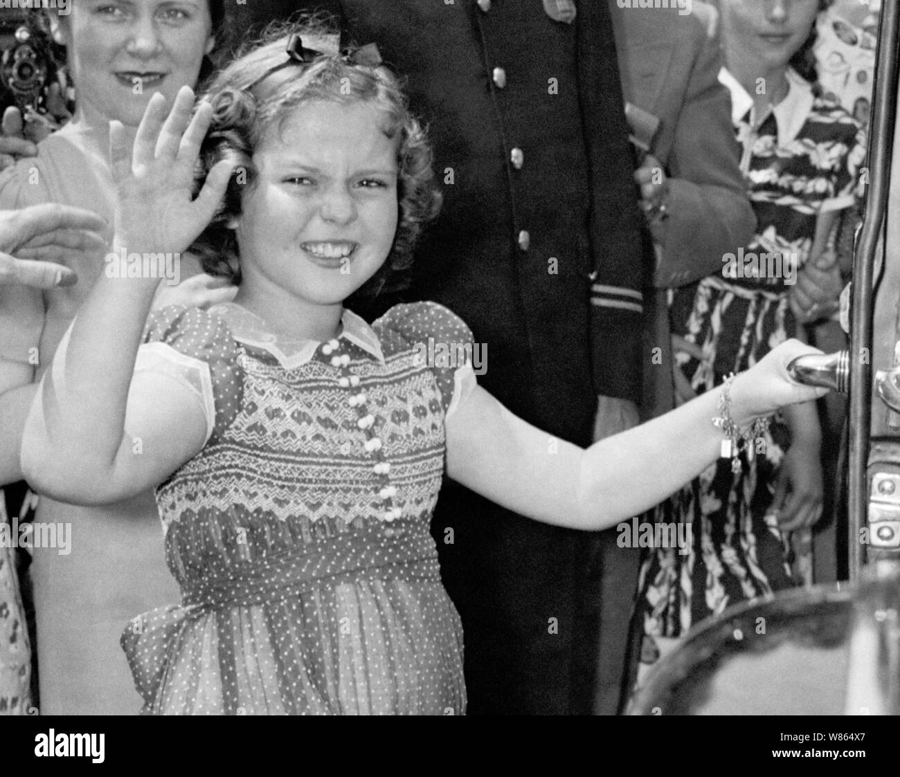 Vintage Foto der amerikanischen Kind Film star Shirley Temple (1928-2014). Das Bild wurde am 24. Juni 1938 gefangen, während die junge Schauspielerin zu den Zuschauern winkte, nachdem Sie das Weiße Haus links nach einem Treffen mit US-Präsident Franklin D Roosevelt. Während Ihrer Konversation Sie erklärte der Präsident, wie sie verloren hatte einen Zahn in der Nacht vor, wenn es fiel aus, als sie ein Sandwich gegessen. Stockfoto