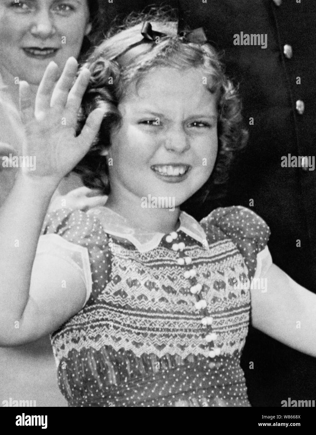 Vintage Foto der amerikanischen Kind Film star Shirley Temple (1928-2014). Das Bild wurde am 24. Juni 1938 gefangen, während die junge Schauspielerin zu den Zuschauern winkte, nachdem Sie das Weiße Haus links nach einem Treffen mit US-Präsident Franklin D Roosevelt. Während Ihrer Konversation Sie erklärte der Präsident, wie sie verloren hatte einen Zahn in der Nacht vor, wenn es fiel aus, als sie ein Sandwich gegessen. Stockfoto