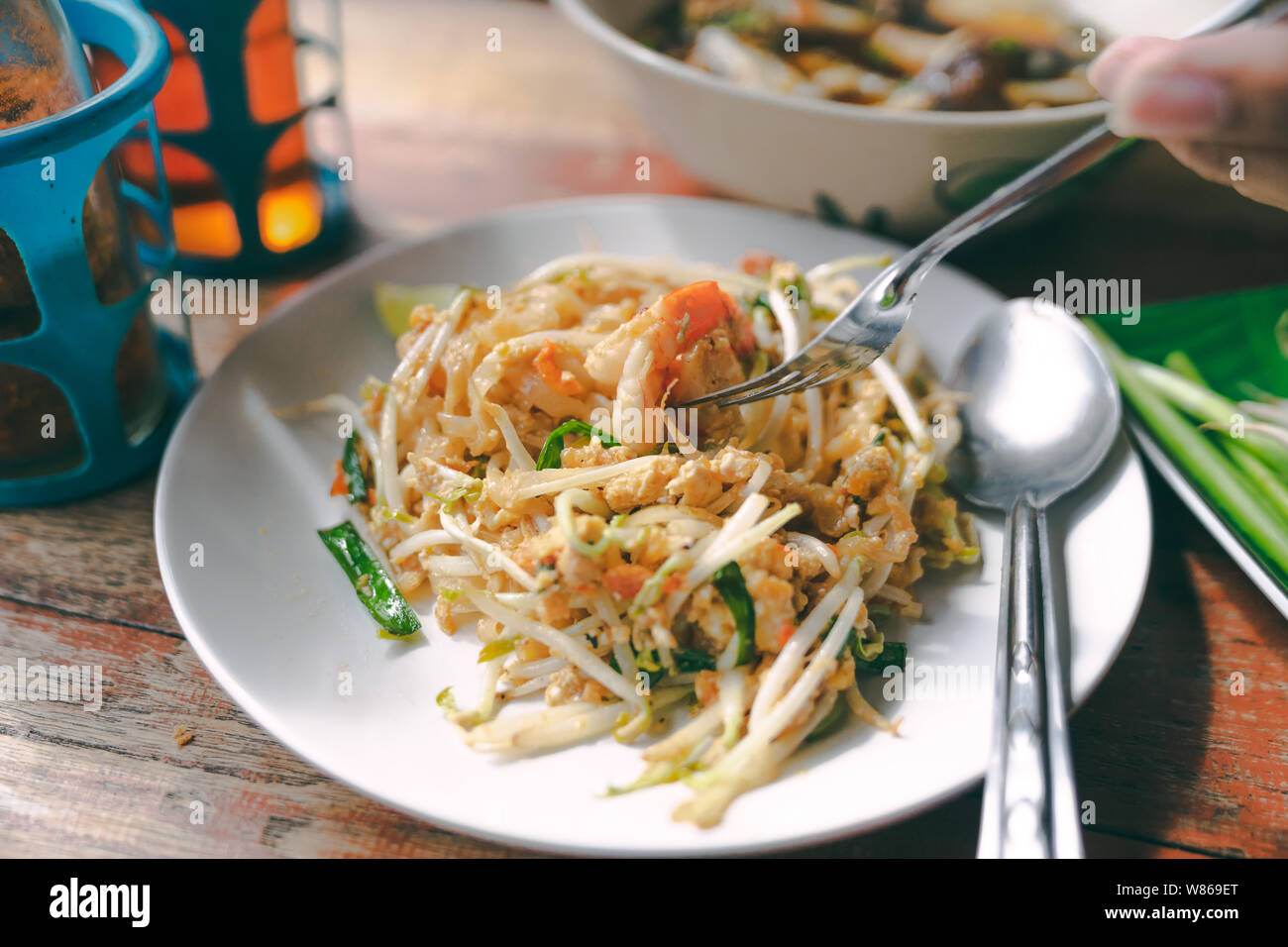 Nahaufnahme Pad Thai Nudeln Thai Street Food auf Holztisch mit Hand und Gabel Stockfoto