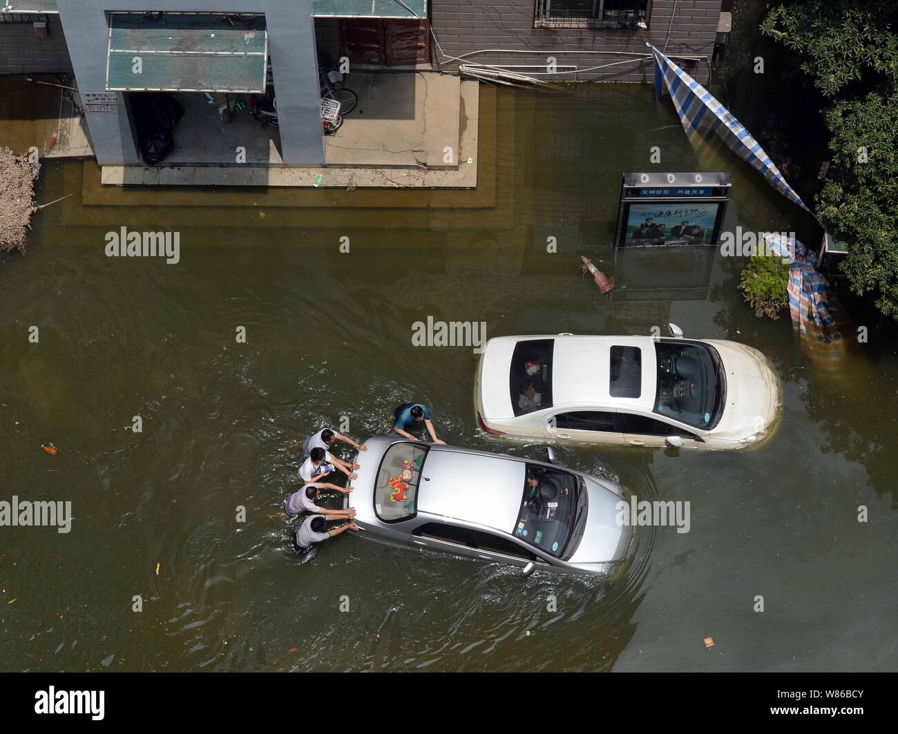 Luftaufnahme der lokalen Bewohner drücken ein Auto in den Fluten durch starken Regen eine Wohn- Projekt in Wuhan City verursacht gefangen, Zentrale Stockfoto