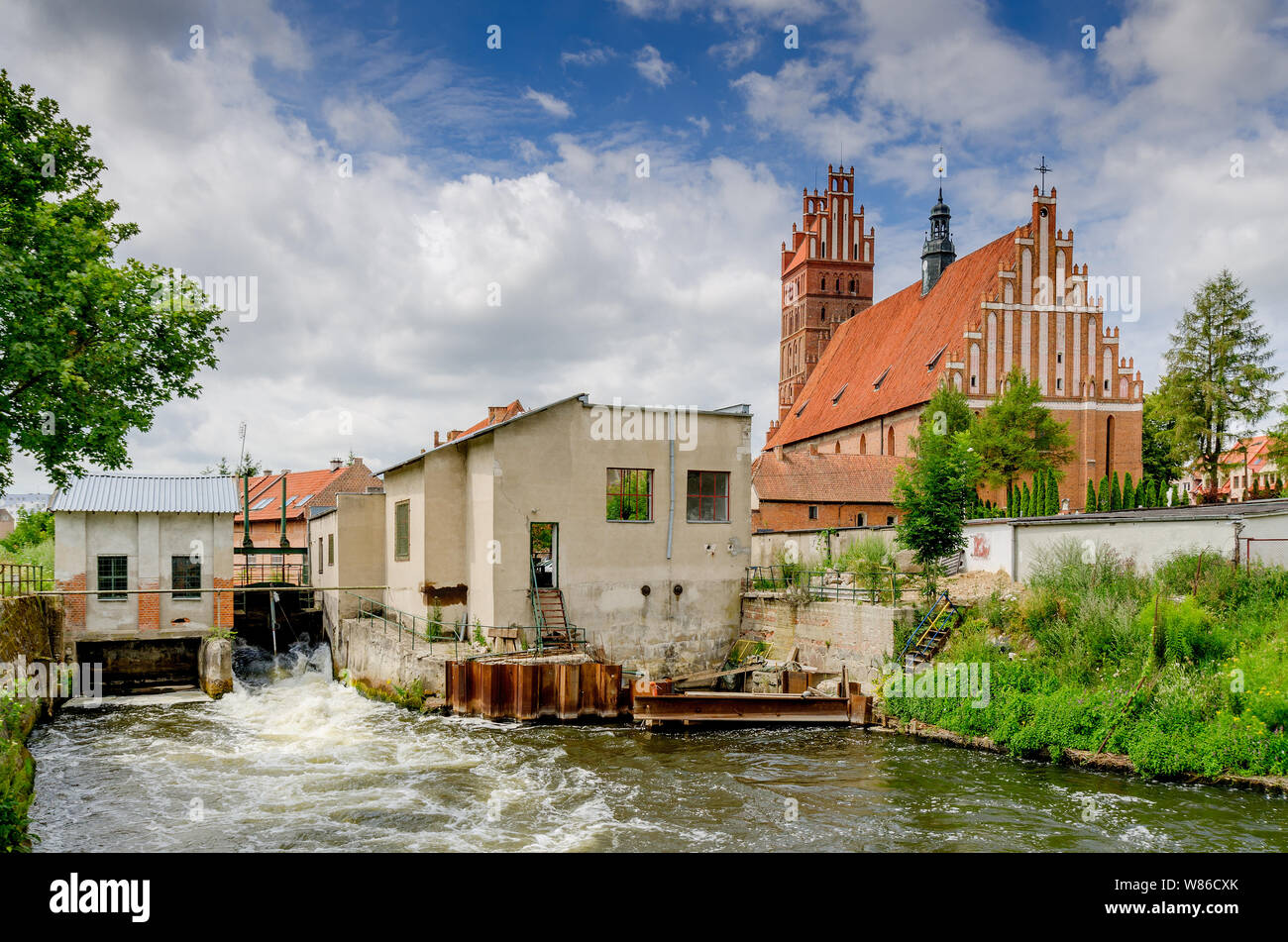 Dobre Miasto, ger. Guttstadt, ermland - masurische Provinz, Polen. Kleines Wasserkraftwerk. Im Hintergrund - 14 Cent. Stiftskirche. Stockfoto