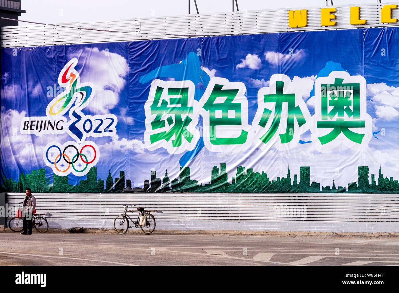 --FILE - Ein chinesischer Mann steht vor einem riesigen banner Förderung der Beijing 2022 Olympischen Winterspiele auf einer Straße in Congli Xiwanzi Stadt, Grafschaft, Zhangji Stockfoto