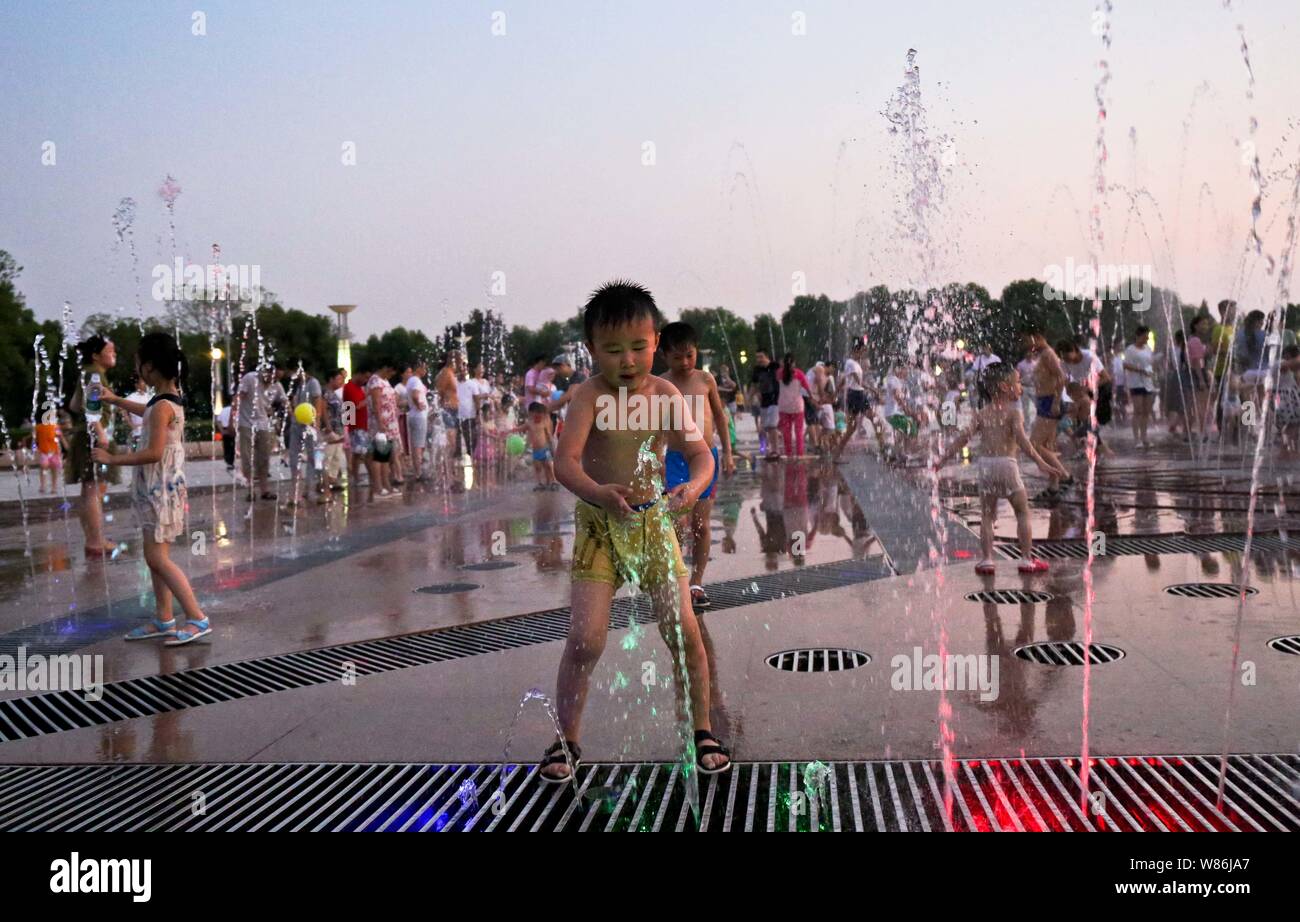 Chinesische Kinder spielen mit Wasser in einen Brunnen aus an einem heißen Tag in Tongling Stadt zu kühlen, der ostchinesischen Provinz Anhui, 25. Juli 2016. Die Hälfte der Stockfoto