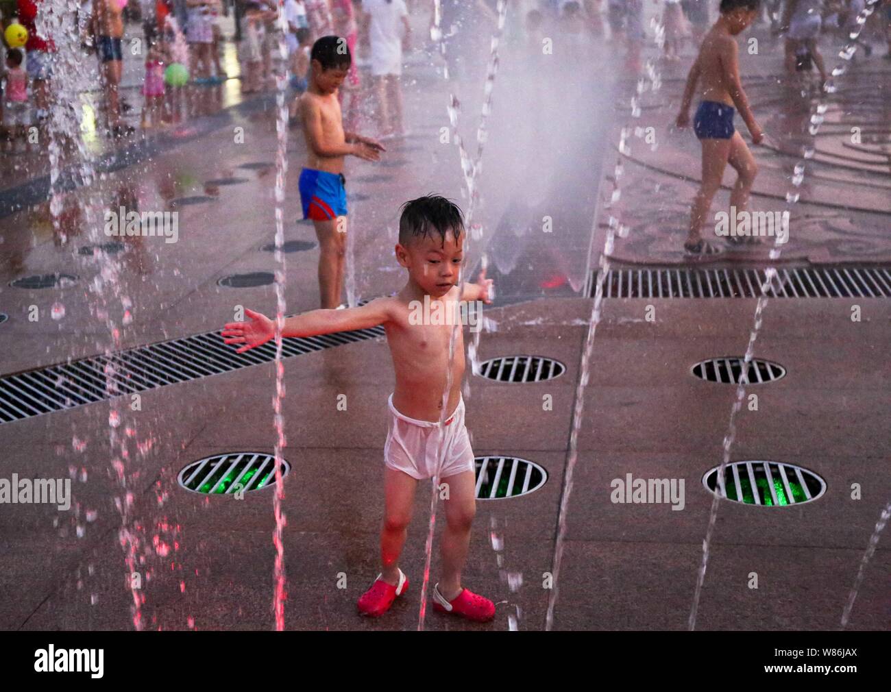 Chinesische Kinder spielen mit Wasser in einen Brunnen aus an einem heißen Tag in Tongling Stadt zu kühlen, der ostchinesischen Provinz Anhui, 25. Juli 2016. Die Hälfte der Stockfoto