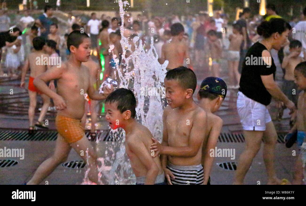 Chinesische Kinder spielen mit Wasser in einen Brunnen aus an einem heißen Tag in Tongling Stadt zu kühlen, der ostchinesischen Provinz Anhui, 25. Juli 2016. Die Hälfte der Stockfoto