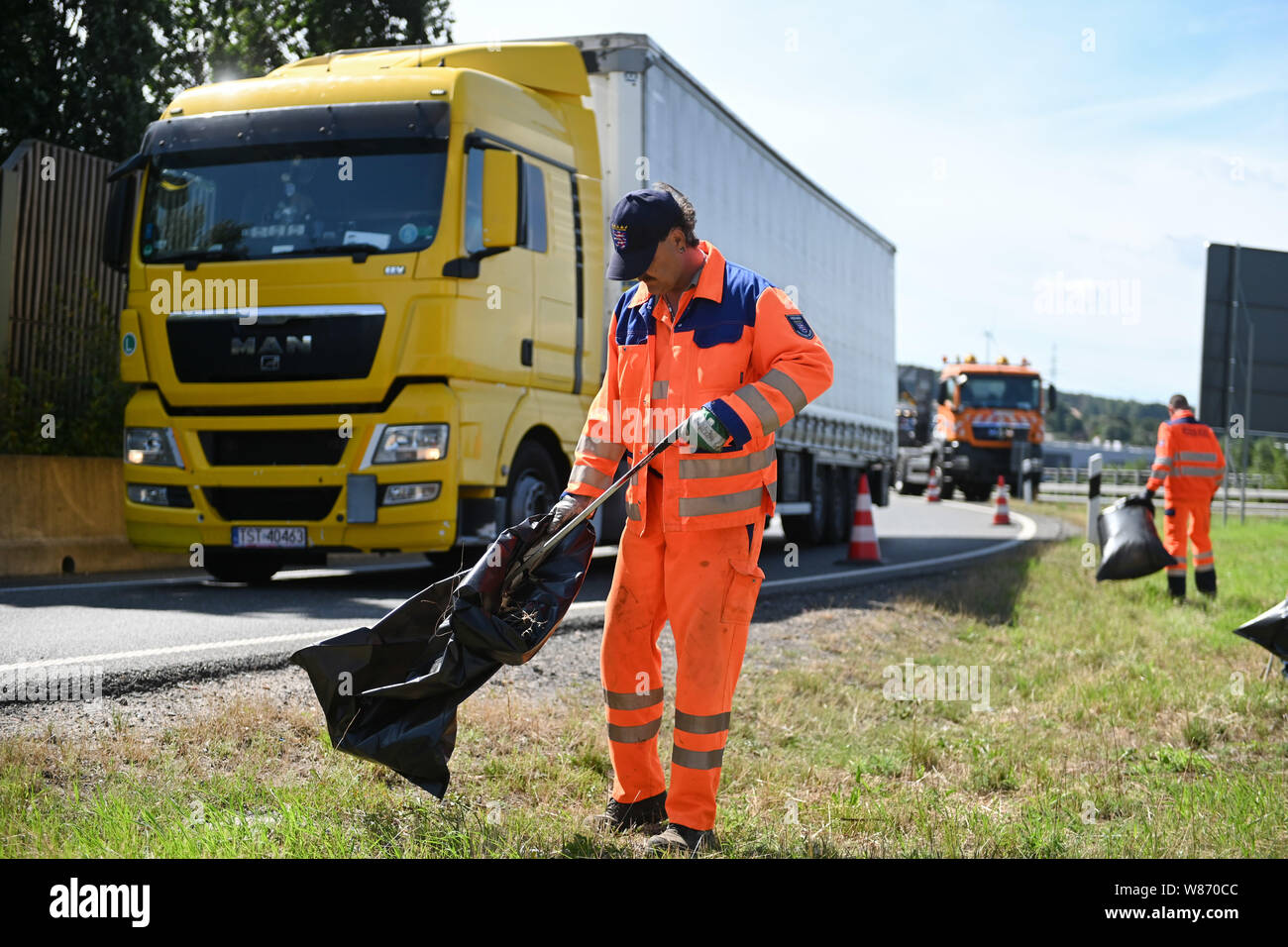 Kassel, Deutschland. 08 Aug, 2019. Mitarbeiter von Hessen Mobil Entsorgen  von Müll aus den grünen Streifen entlang der Zufahrt zur Autobahn A7. Durch  das Sammeln von Abfall, sie lenken die Aufmerksamkeit auf